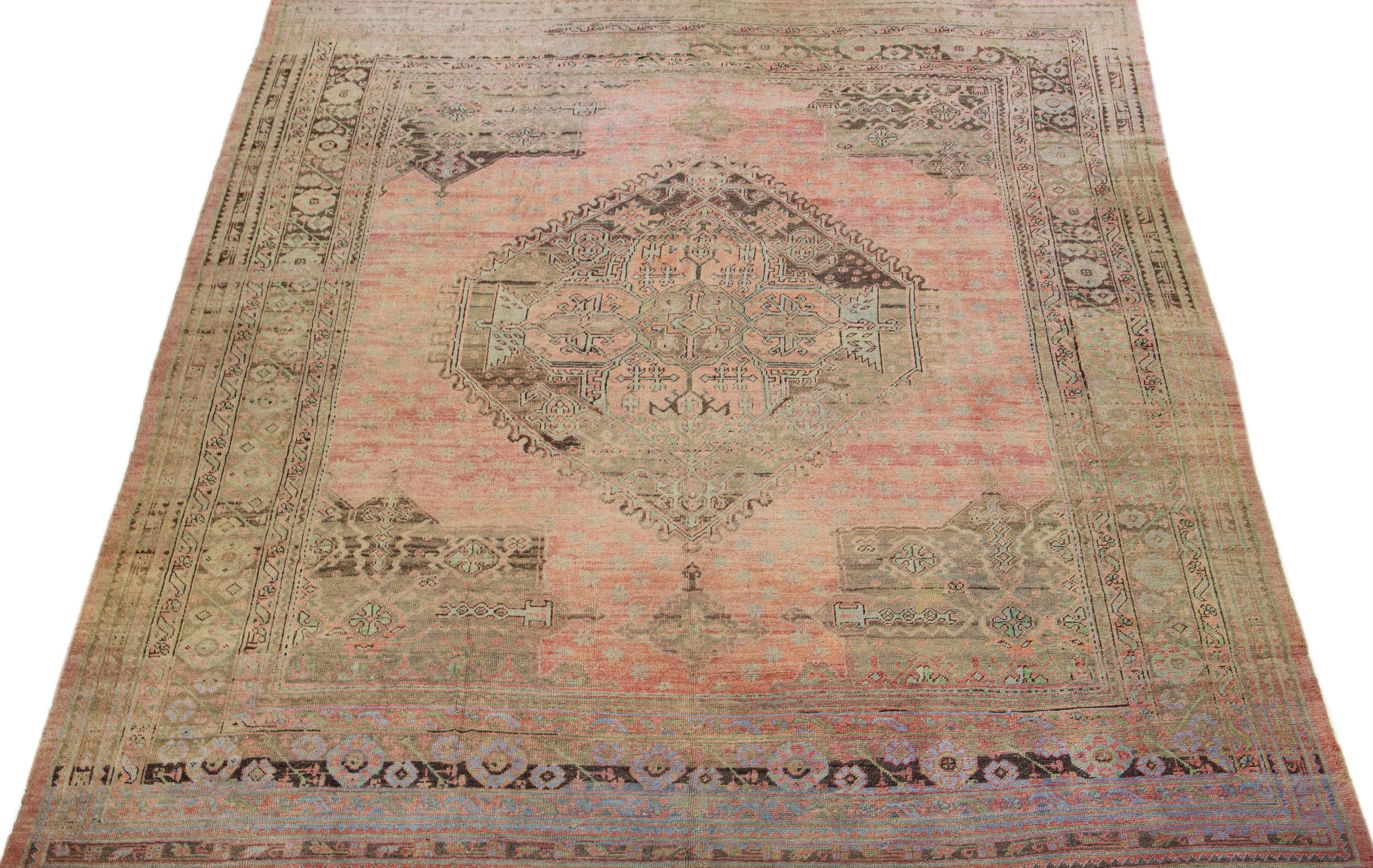 Beautiful Antique Oushak hand-knotted wool rug with a rose color field. This Piece has green, gray, and blue accent colors in a gorgeous all-over medallion design.

This rug measures: 13'2