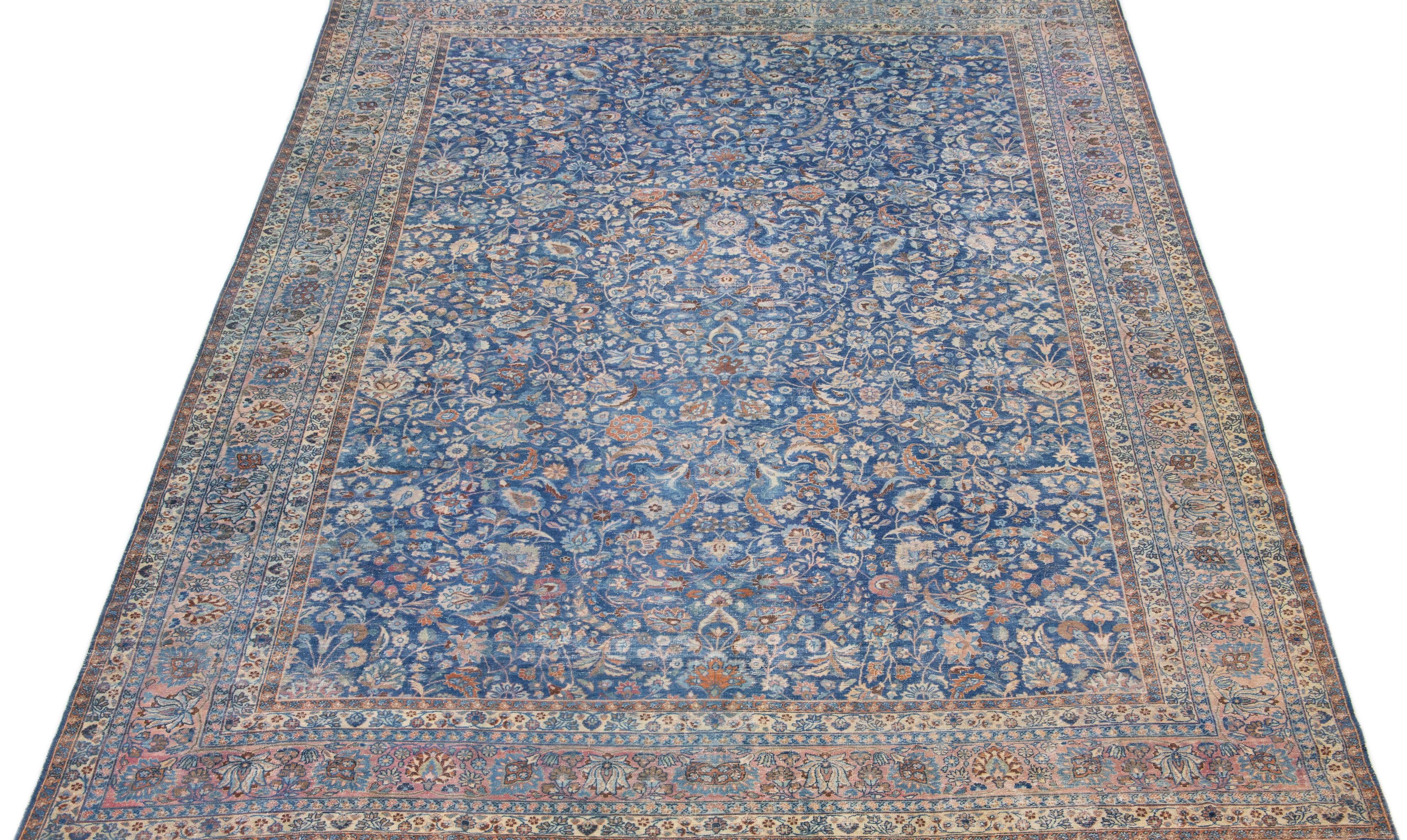 This luxurious Antique Mashad wool rug features a blue color field, with a rose-framed, Classic floral pattern accentuated by beige details.

This rug measures: 12' x 17'8