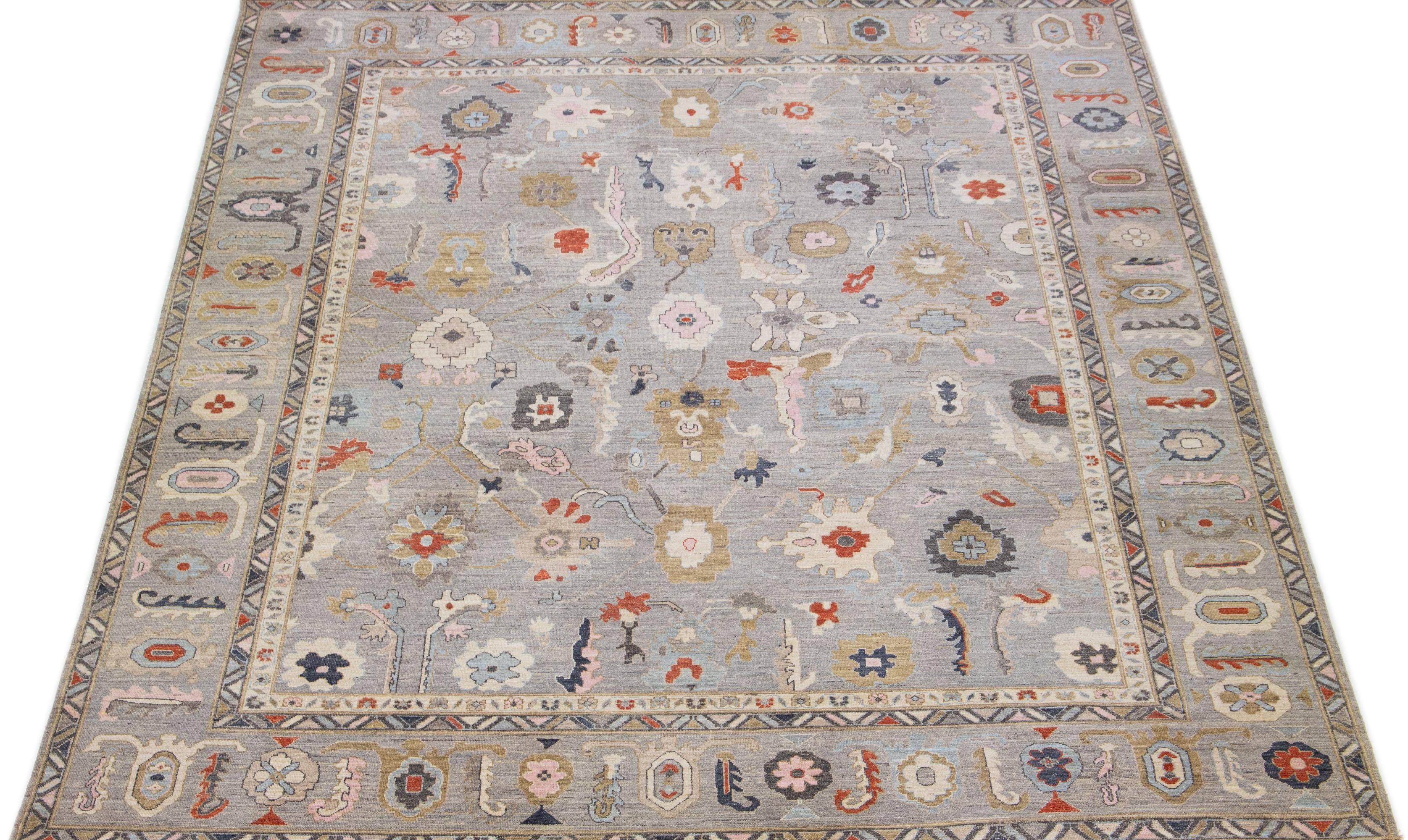 An exquisite oversized Sultanabad hand-knotted wool rug is presented, showcasing a stunning gray field with a design frame. The rug further highlights rust, blue, and pink accents in a breathtaking floral motif that embellishes the entire rug