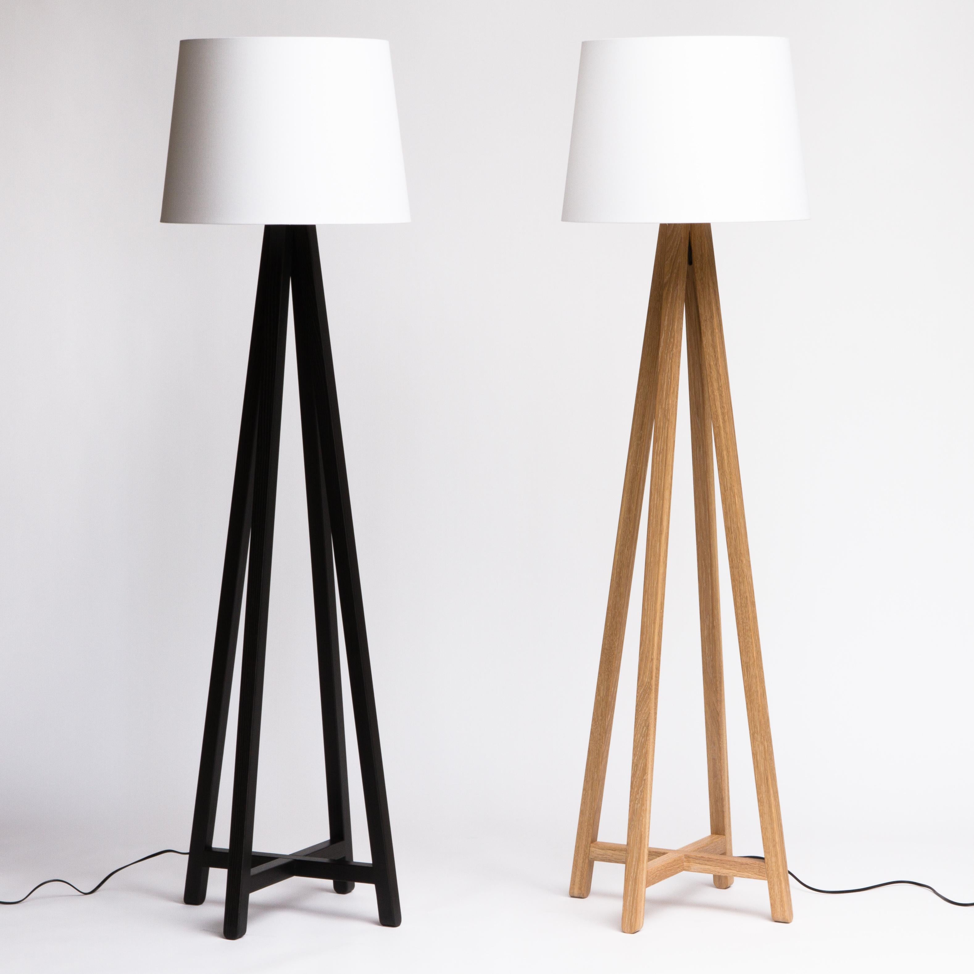 The Alpha floor lamp features a conical drum shade supported by a tapered framework of slender wooden legs. The lamp cord is hidden inside one of the legs to maintain a clean, uncluttered appearance.

Shown here is the 6’-tall Alpha Plus lamp. A