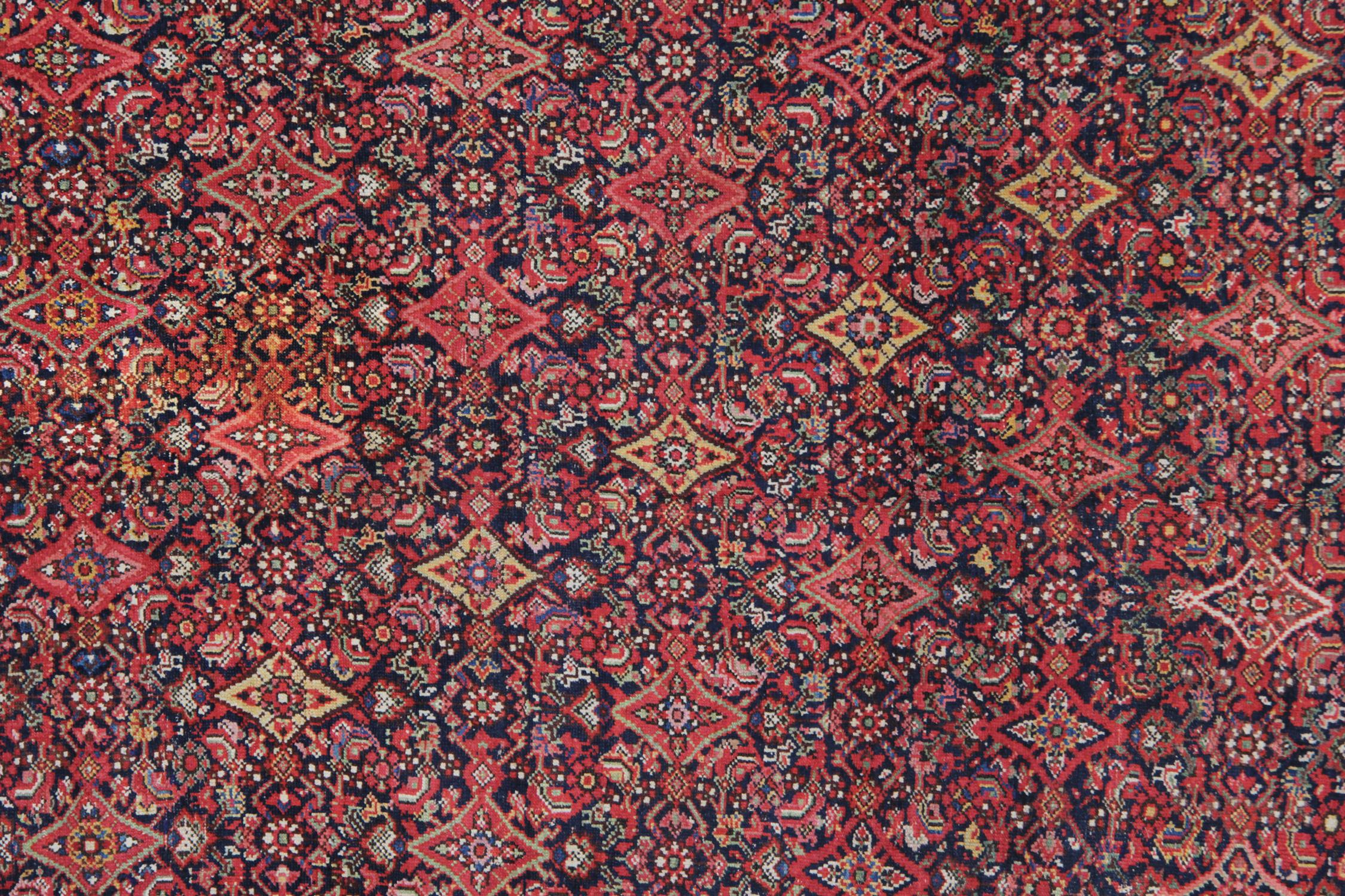 A fine antique wool rug was woven by hand in the late 19th century, circa 1880. It features an intricate all-over design through the centre, with beautiful colours of orange, brown and red colourways. The repeat, symmetrical pattern with eyecatching