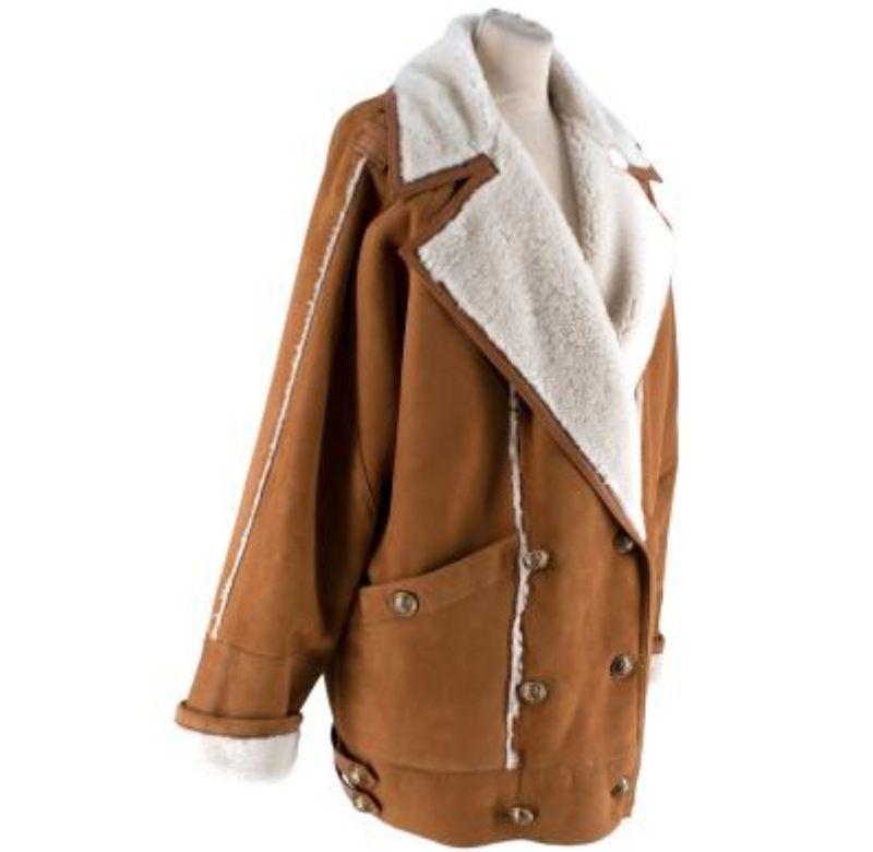 Balmain Shearling and Suede Beige Coat
  
 - Double breasted 
 - Gold tone logo button details 
 - Front button pocket on each side 
 - Decorative leather straps on the bottom of each side and on each shoulder 
 

 Materials 
 100% Lambskin 
 

