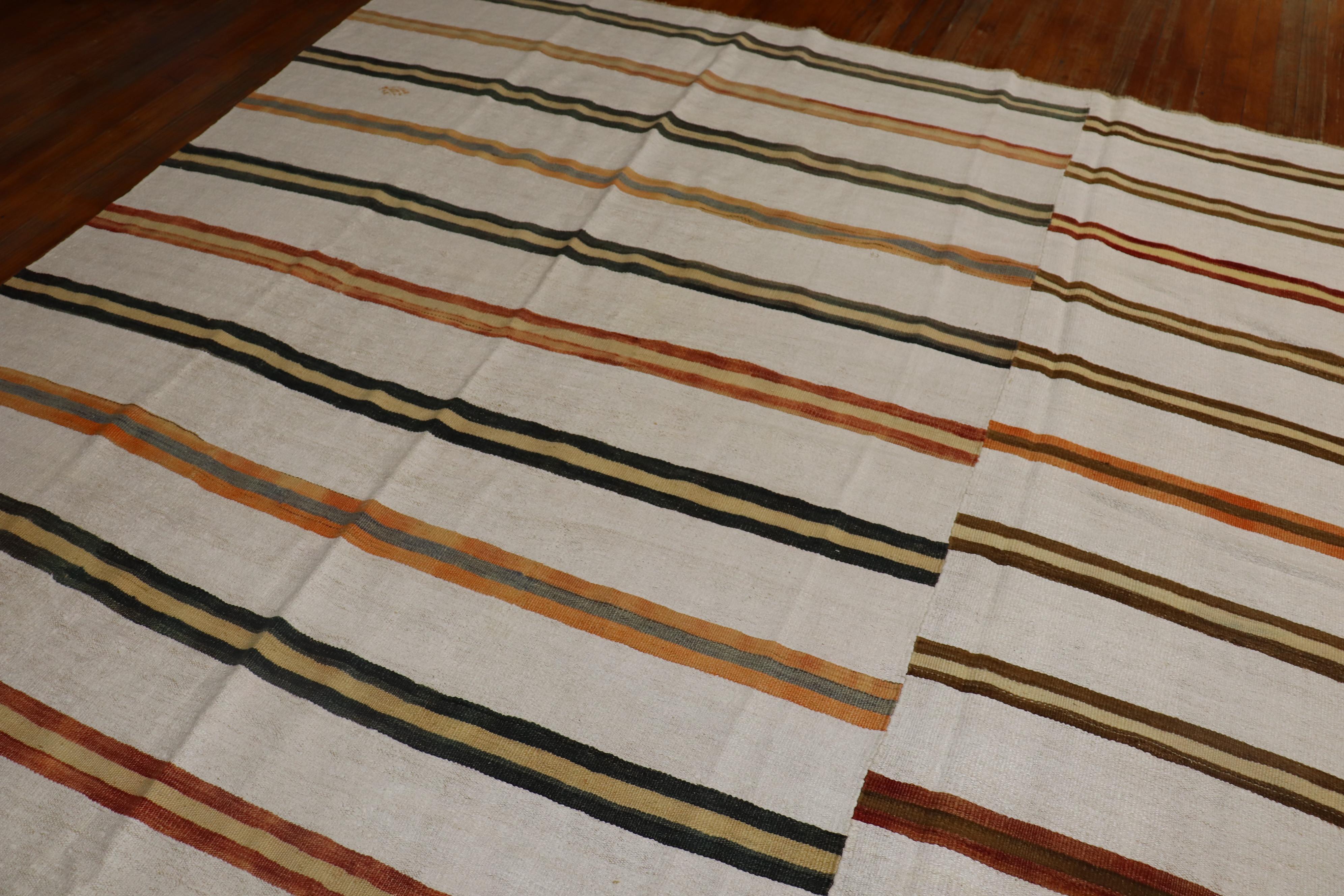 A large square turkish klim with a rustic stripe pattern on an ivory background from the third quarter of the 20th century.

Measures: 12'6