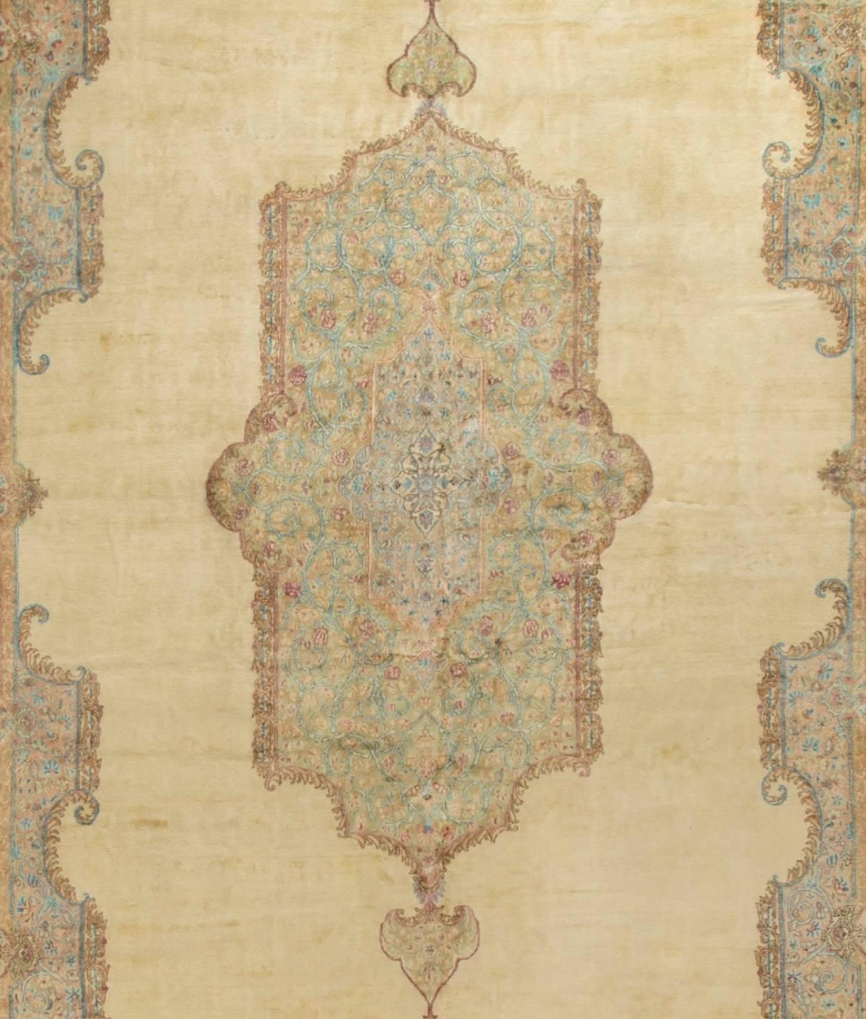 Übergroßer persischer Kirman-Teppich um 1940. Das zart cremefarbene Feld umgibt ein wunderschön detailliertes zentrales Medaillon in sanften Blautönen, das von einer wunderbar geschwungenen Bordüre ergänzt wird. Gewebt in der persischen Stadt Kirman