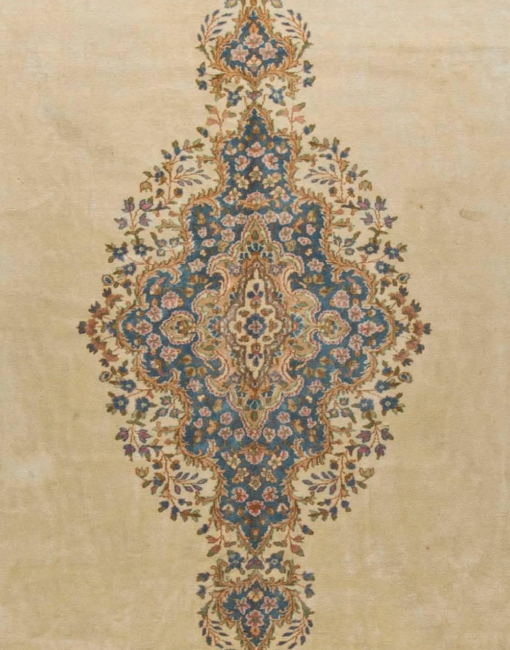Oversize vintage Persian Kirman rug. The ivory field with a lovely central medallion in blues, with goldy-browns all surrounded by a wonderfully detailed border with identical colors. Kirman is the capital of the province in south Persia of the same