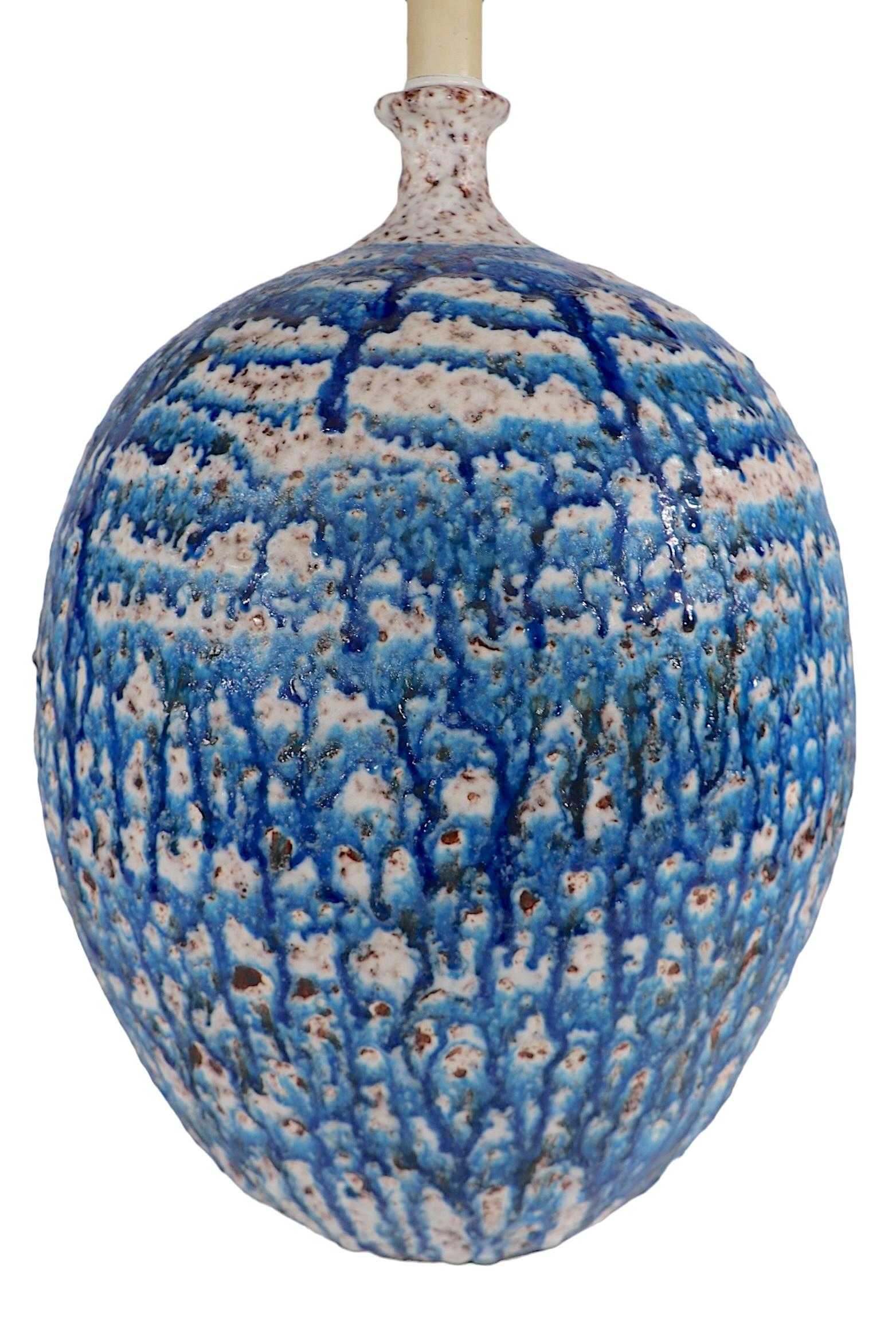 Impressionnante lampe de table en céramique surdimensionnée  glaçure volcanique texturée dans des tons de bleu et de sable.  La lampe est dotée d'un large corps bulbeux  avec une petite forme de téton en haut. La lampe est en très bon état de