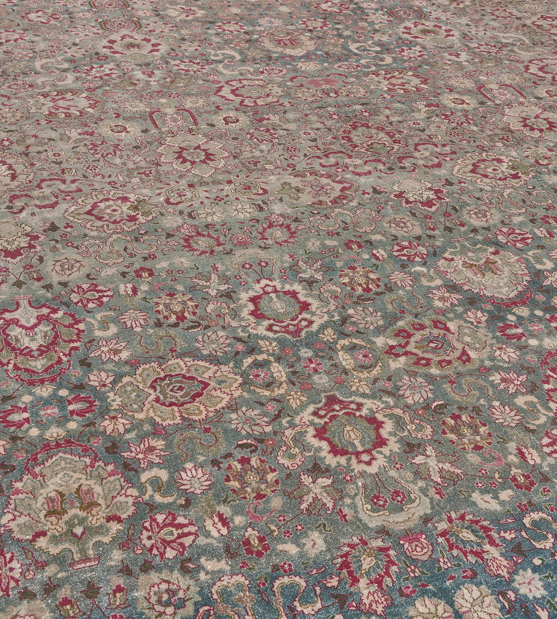Questo antico tappeto indiano Agra, risalente al 1900 circa, ha un campo verde mare sfumato con un disegno generale di palmette in grassetto color avorio, verde muschio, rosa polveroso e rosso bordeaux collegate da una vite floreale e frondosa, in