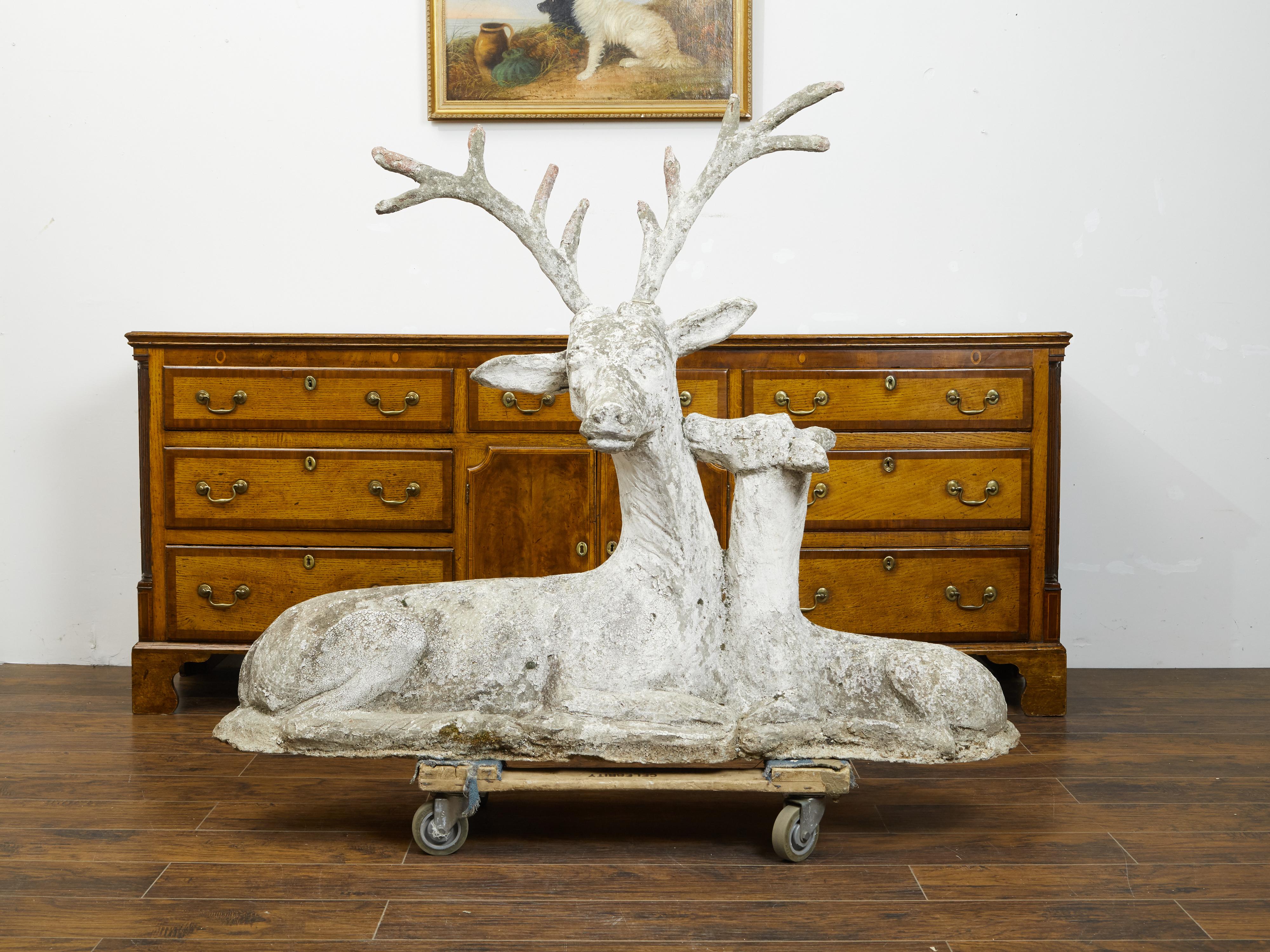 An oversized English carved stone deer group from the early 20th century, with great patina. Created in England during the first quarter of the 20th century, this large and heavy sculpted group charms us with its depiction of a reclining stag topped