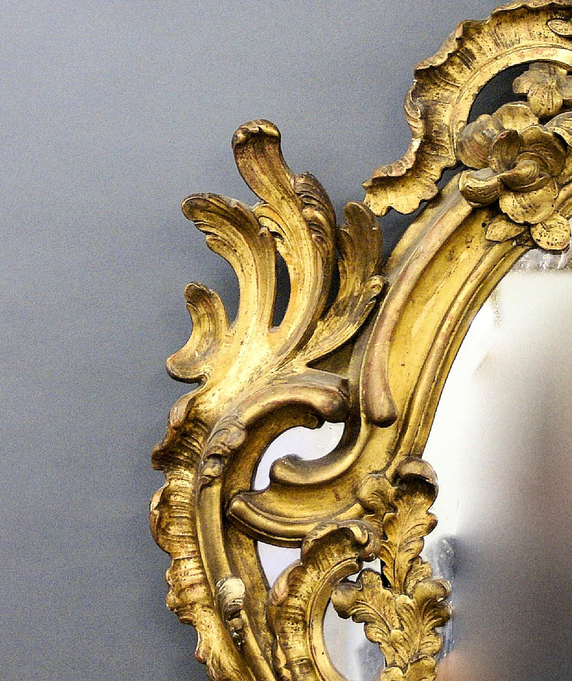 This beautiful and very large 19th C. carved wood gilt French wall mirror is Rococo in style and retains its original gilding, mirror plate and backing all in very good condition. The markings and blemishes commensurate with the age and does nothing