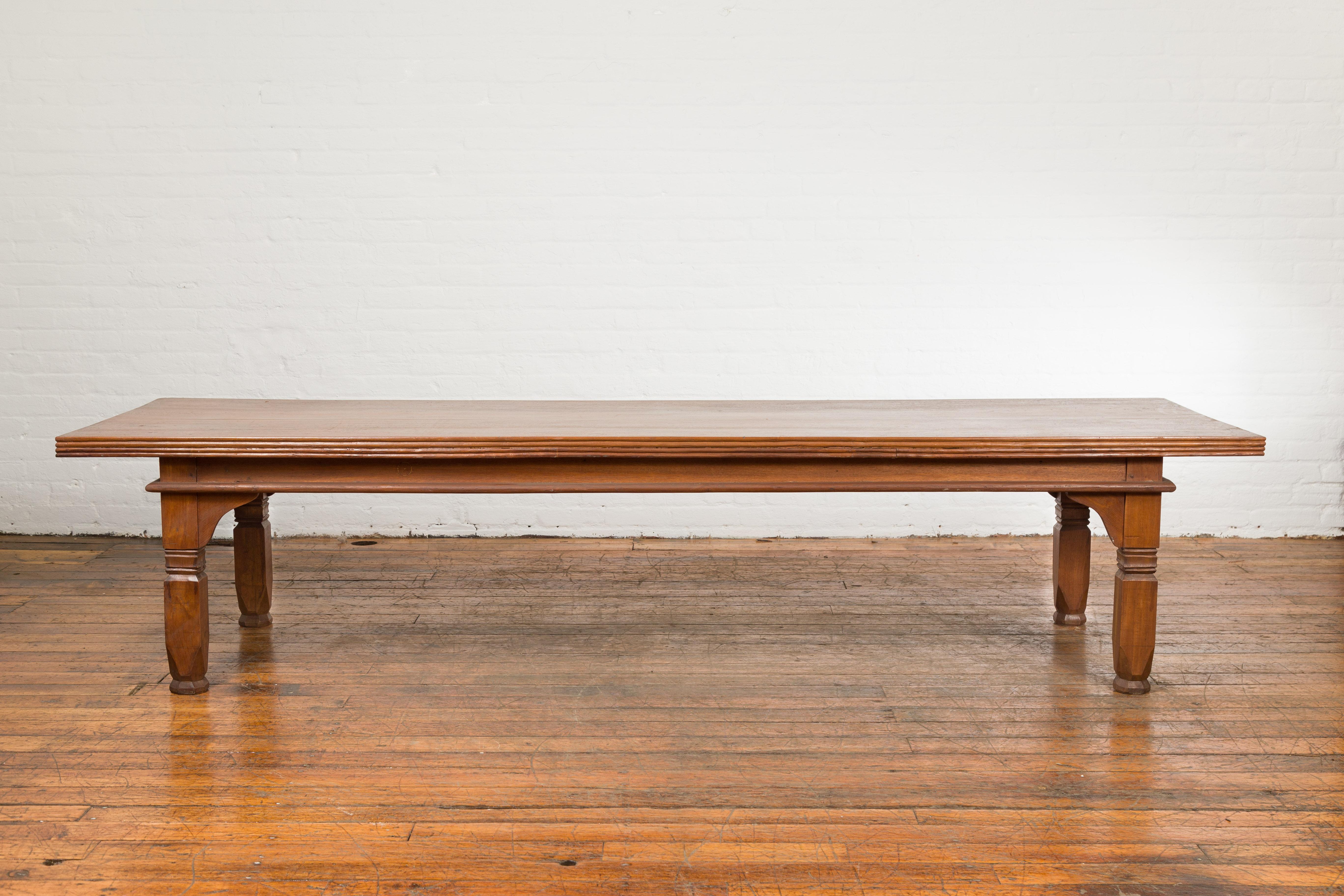 An oversized Indonesian coffee table from the 19th century, with reeded accents and carved legs. Created in Indonesia during the 19th century, this Indonesian coffee table features a rectangular planked top with reeded motifs on the edge, sitting
