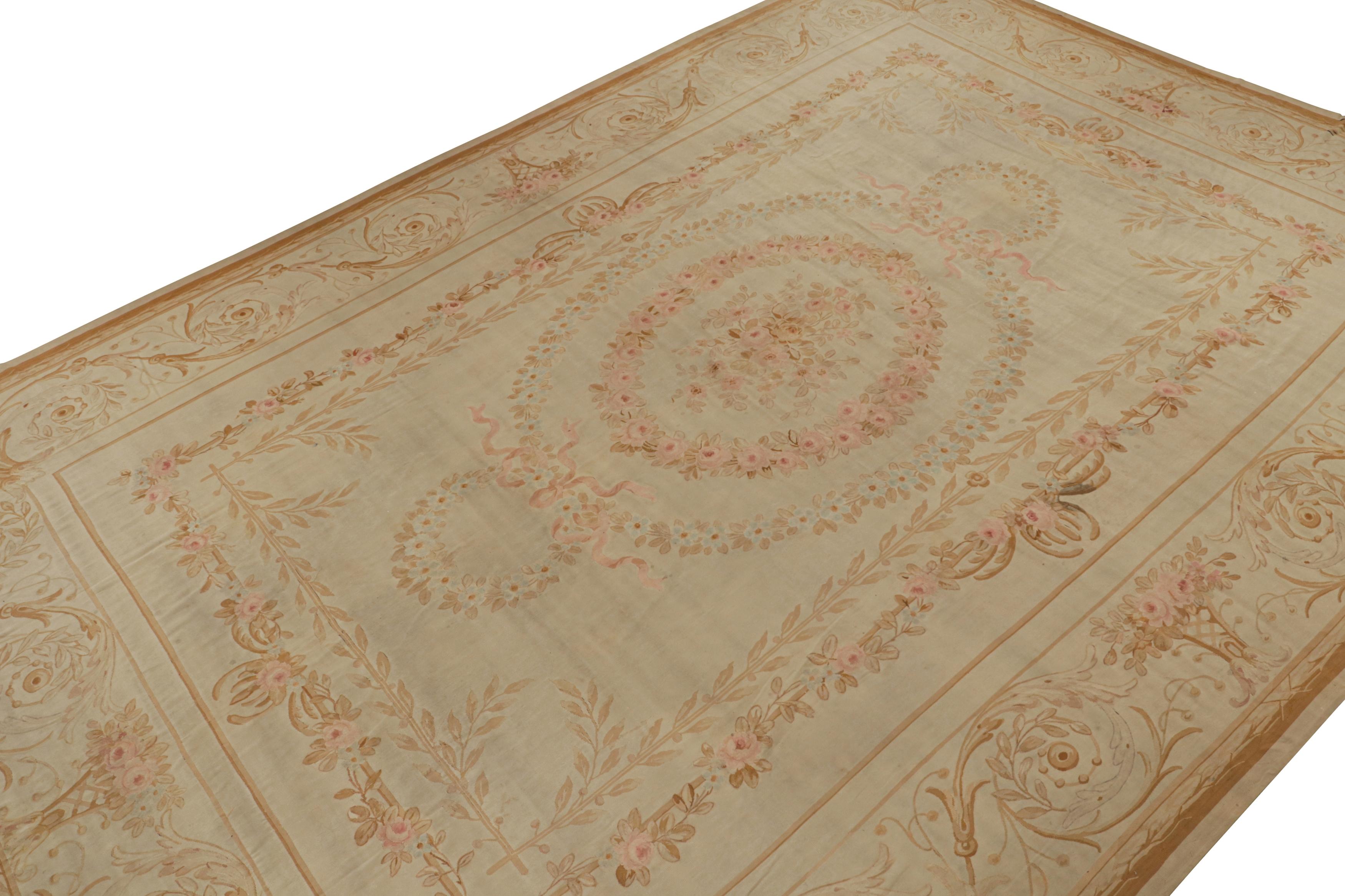 Handwoven in wool circa 1890-1900, this 13x20 antique Aubusson flatweave and oversized rug is an extremely rare turn-of-the-century curation. Its design enjoys beige and cream undertones, with light blue and pink floral patterns around several large