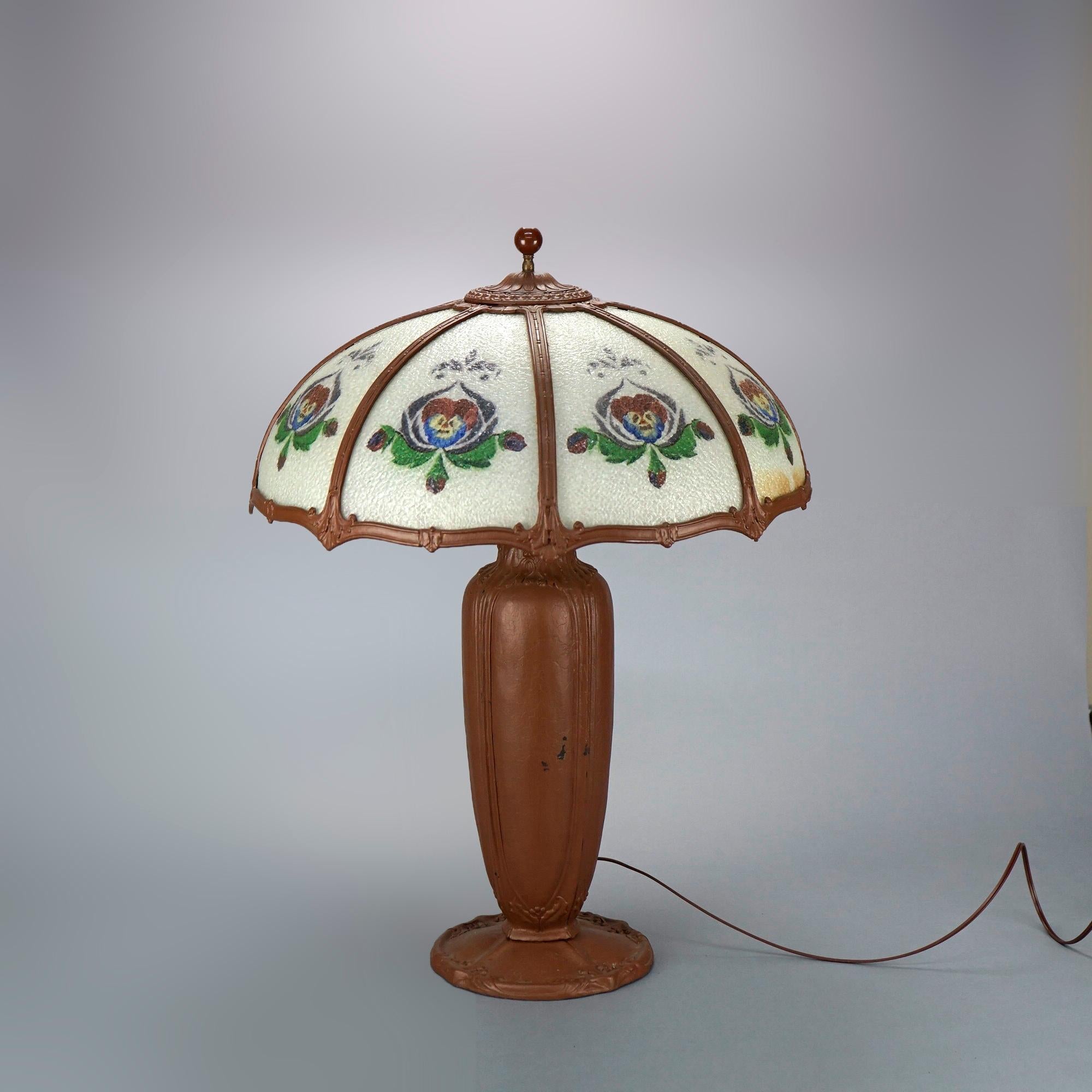 Eine große antike Tischlampe in der Art von Bradley und Hubbard bietet einen kuppelförmigen Schirm mit gebogenen Glasscheiben, die mit stilisierten Blumen auf der Rückseite bemalt sind, über einem urnenförmigen Dreifach-Sockel, um 1920

Maße: 28''H