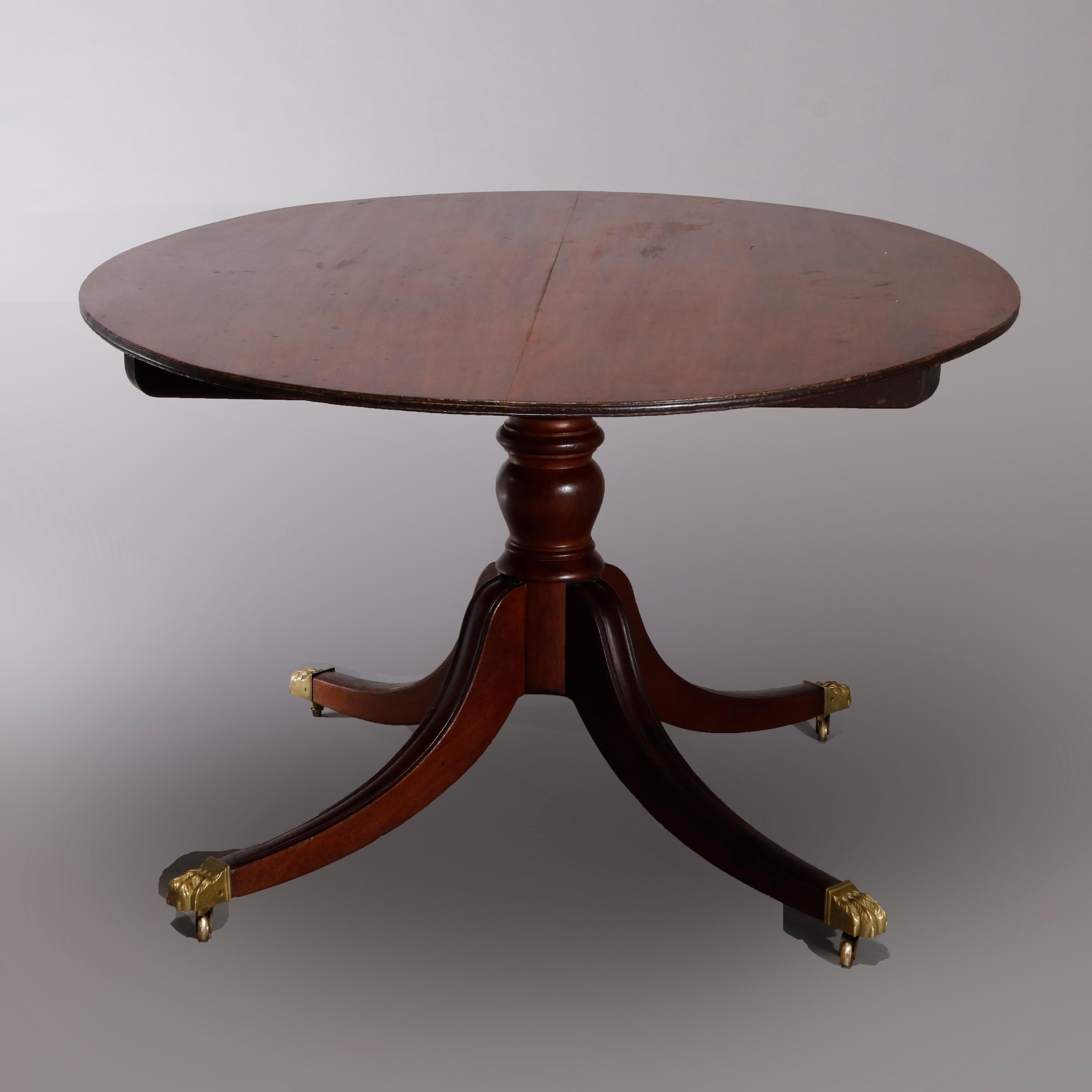 An antique English Regency oversized tilt-top table offers mahogany construction with oval top surmounting turned column pedestal raised on convex legs terminating in cast brass paw feet, circa 1830.

Measures: 27.75