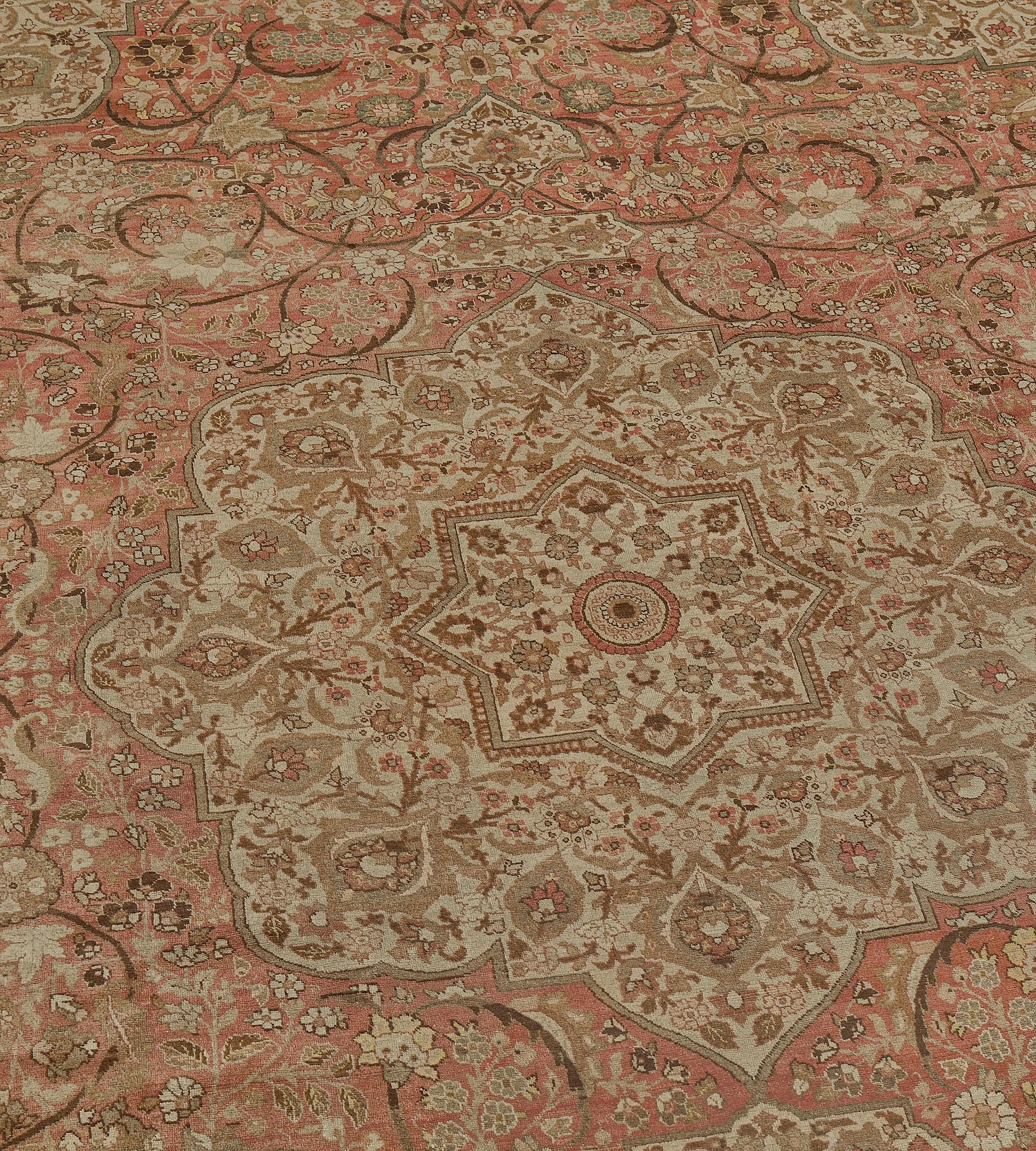 Questo tappeto tradizionale di Tabriz, tessuto a mano, presenta un campo centrale rosso mattone con palmette che emettono viticci floreali e viticci scolastici, che racchiude un medaglione arabescato centrale, con simili quarti di medaglione, in un