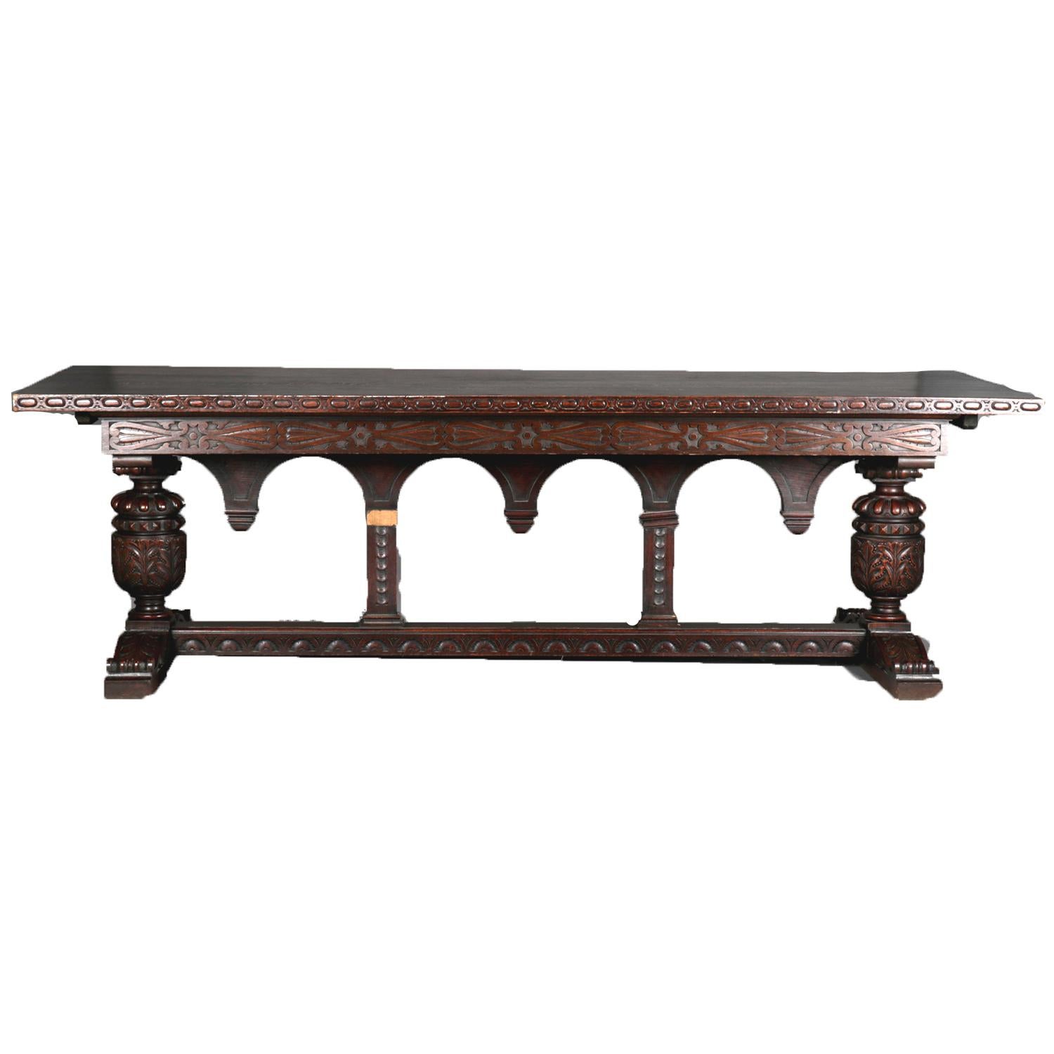 Oversized antique Jacobean trestle dining or conference table features oak construction with top having carved edge decoration above carved scroll caved skirt and supported by acanthus trestle legs flanking supporting legs interspaced with carved