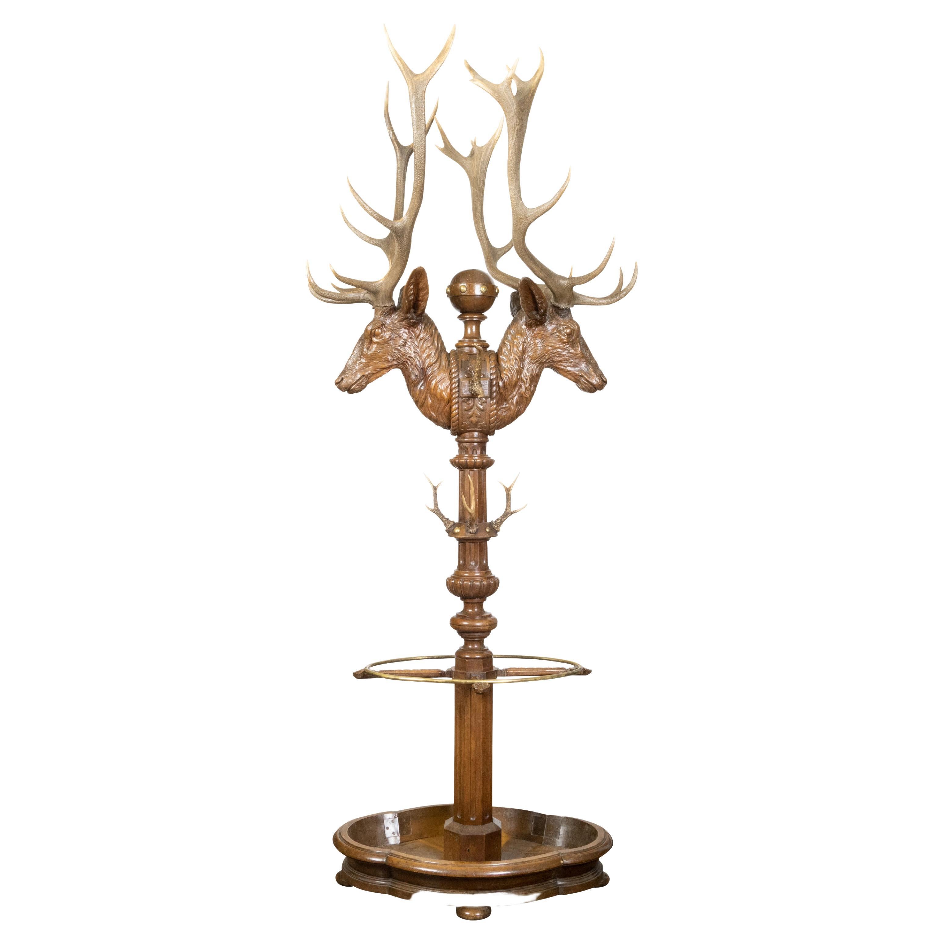 A black forest oversized carved oak coat and hat rack from the 19th century depicting stags with antlers and umbrella stand. Created during the 19th century, this stunning black forest rack captures our attention with its oversized proportions and