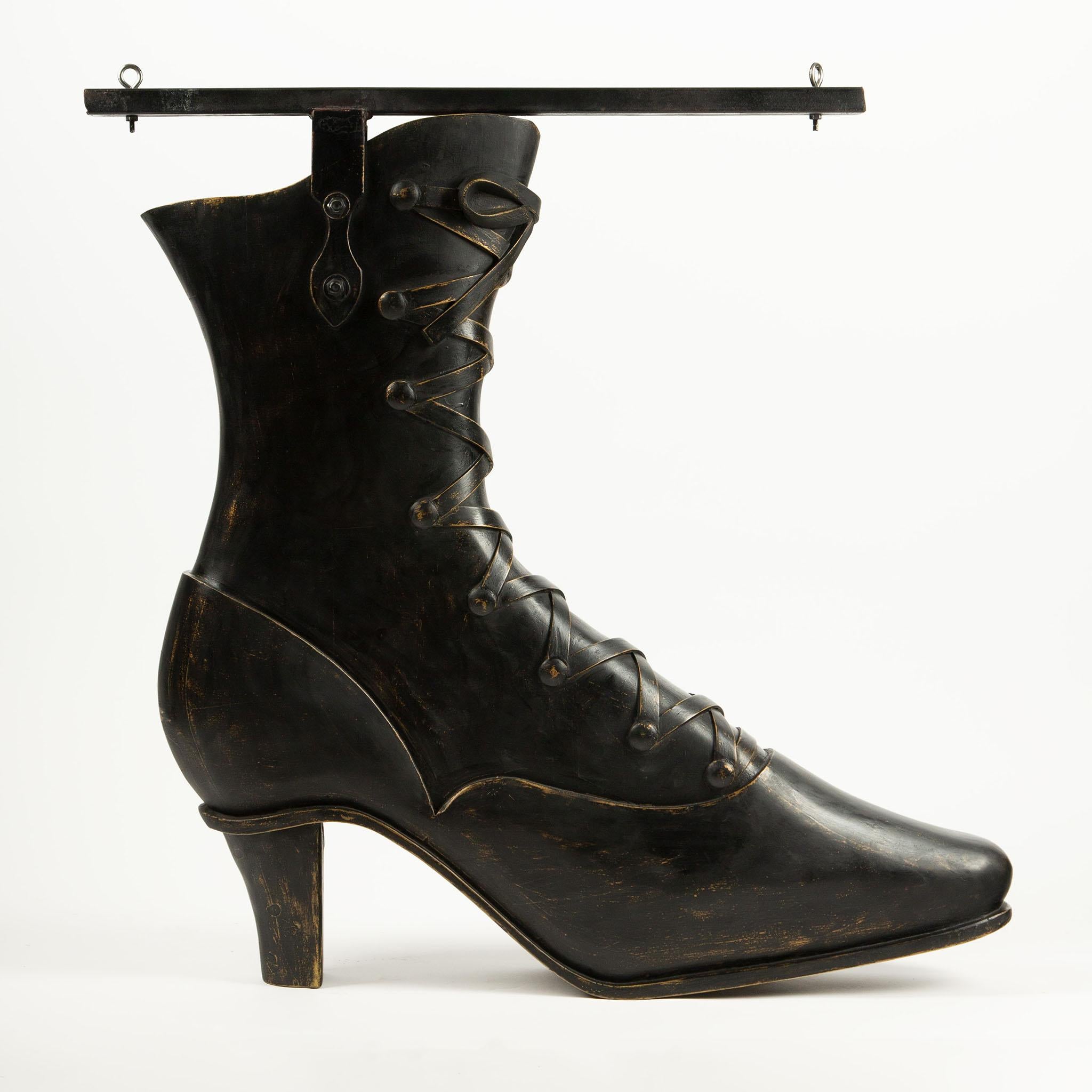 Letrero de zapatero tallado de gran tamaño, principios del siglo XX Un llamativo letrero de zapatero tallado a mano en madera maciza y modelado como un botín victoriano con cordones, punta afilada y tacón apilado, acabado en pintura negra desgastada