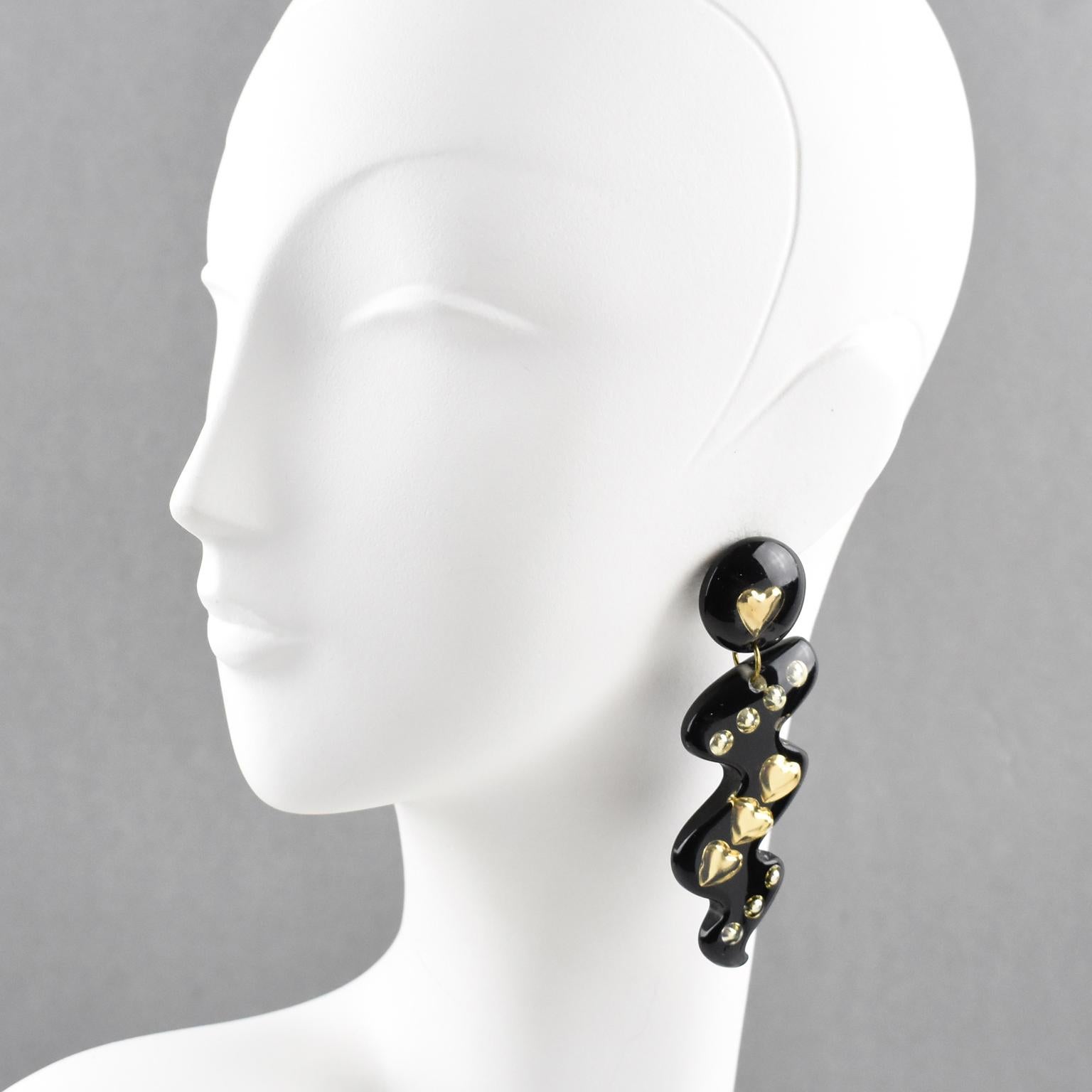 Impressive Italian Lucite dangling clip-on earrings. Oversized zig-zag shape in true licorice black color with gilded heart and bead inclusions. There is no visible maker's mark.
Measurements: 3.63 in. long (9.2 cm) x 1.19 in. wide (3 cm).