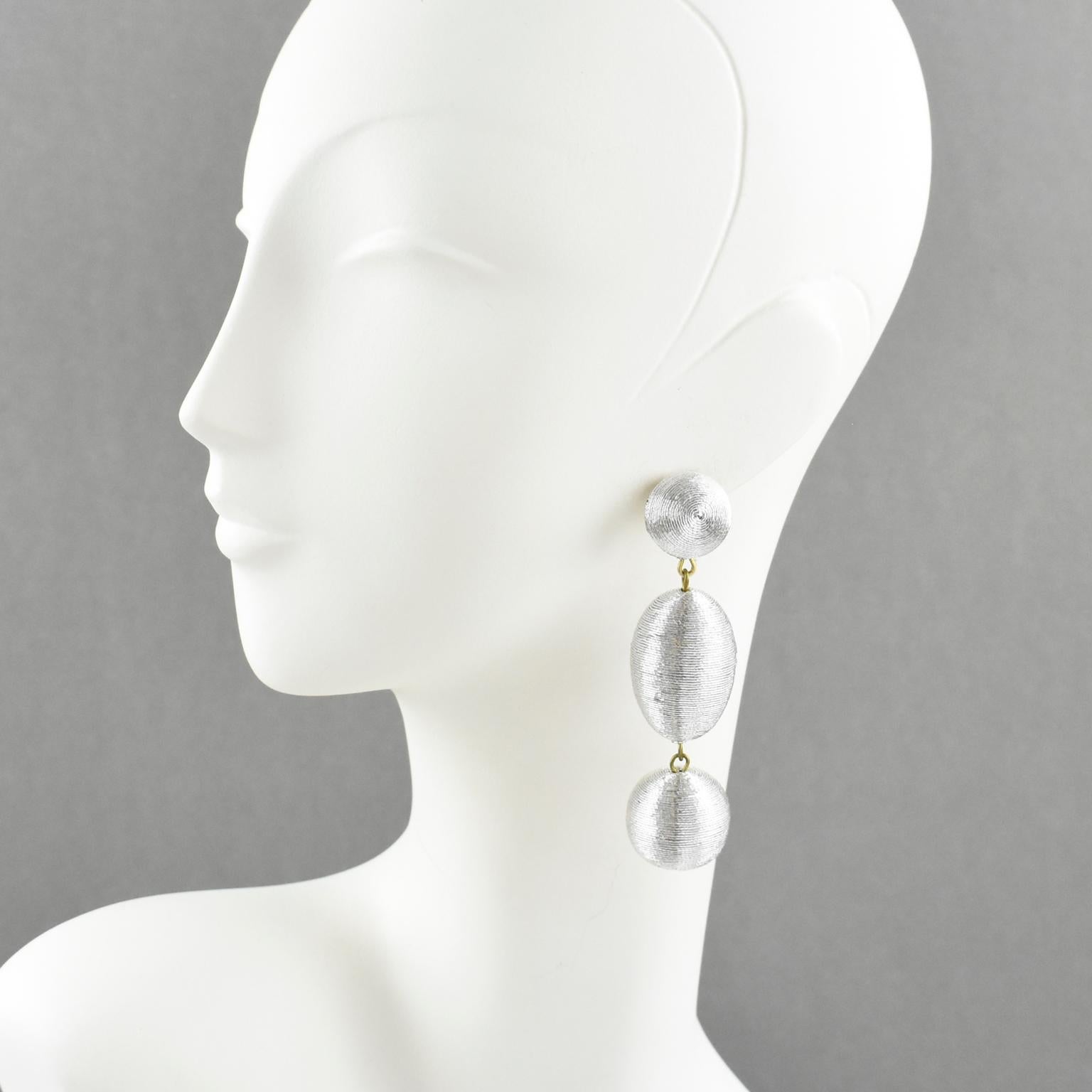 Disco perfection, these pierced earrings have a vintage look. They feature an oversized chandelier dangle shape with a ball and olive elements, all wrapped with silver metallic thread. There is no visible maker's mark. They are for pierced