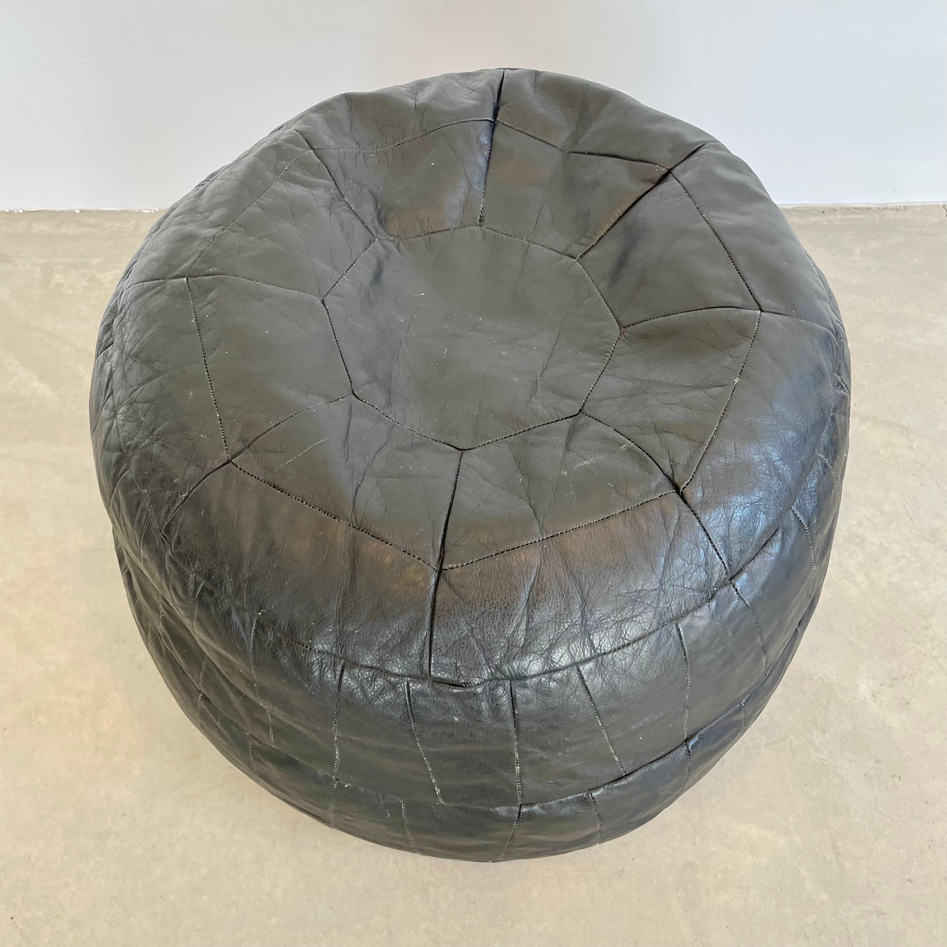 Sophisticated black leather pouf/ottoman by Swiss designer De Sede with triangular patchwork and a final octagonal leather patch at the top. This pouf is in a slightly larger size. Handmade with wonderful faded patina. Gorgeous accent piece. Good