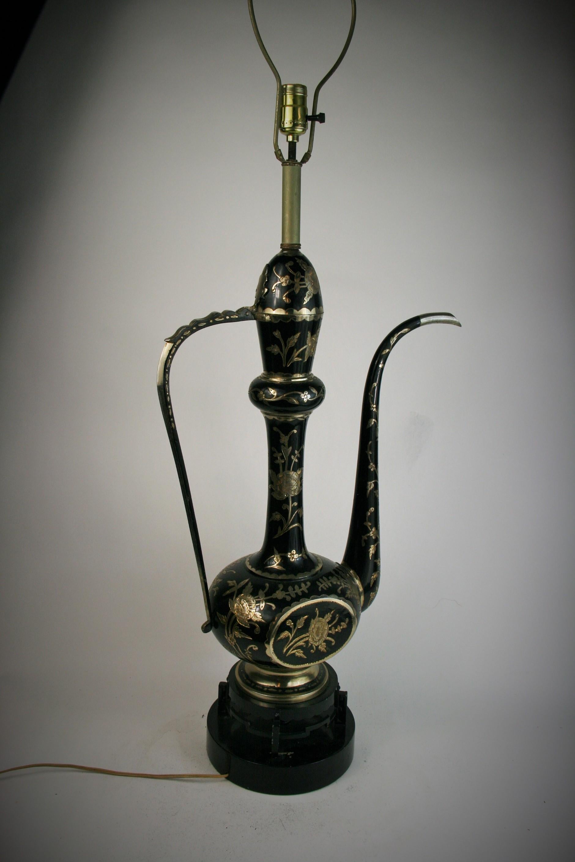 2-298 black enameled etched silver plated brass ewer shaped tall table lamp. The lamp has decorative cut outs in the black enamel making intricate floral and leaf designs.
Set on a double base of metal and lacquered wood.
Original wiring in working