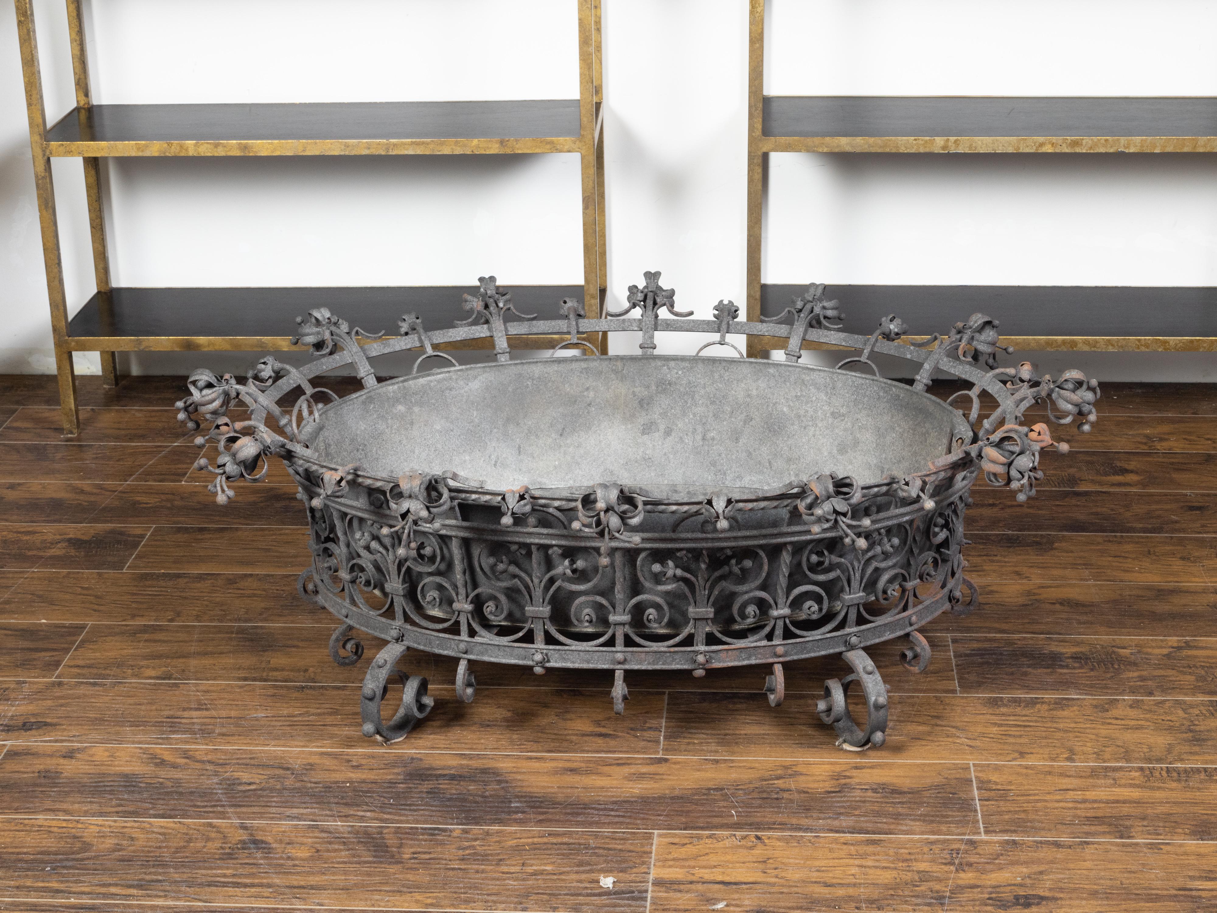 An oversized French iron planter from the early 20th century, with scrollwork and liner. Created in France at the Turn of the Century, this large planter captures our attention with its skillfully executed flaring structure adorned with an abundance