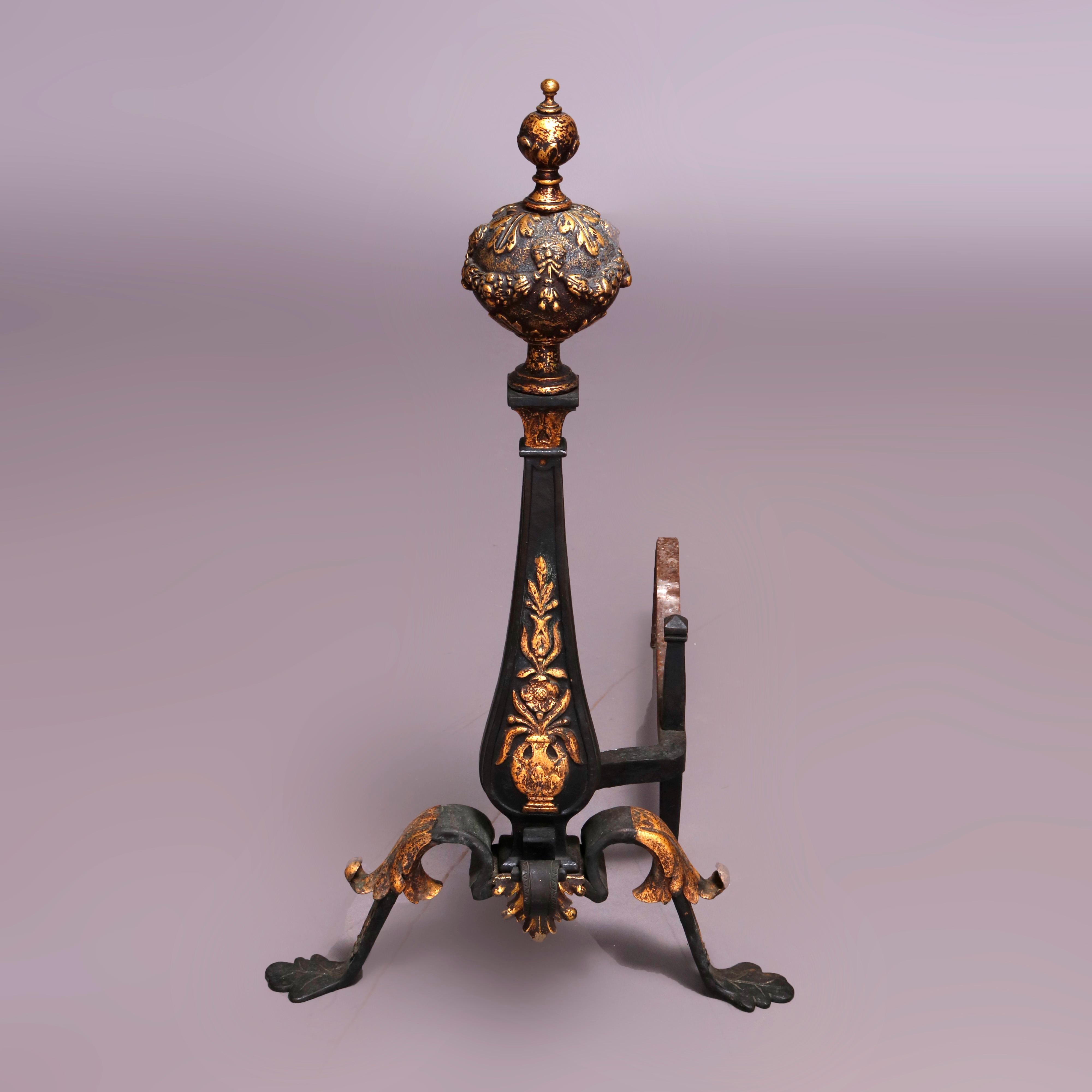 An antique and large French Louis XV fireplace set offers ebonized wrought iron andirons having stlized urn form with gilt panier de fleurs surmounted by high relief foliate ball finial and raised on legs with gilt acanthus knees and stylized paw