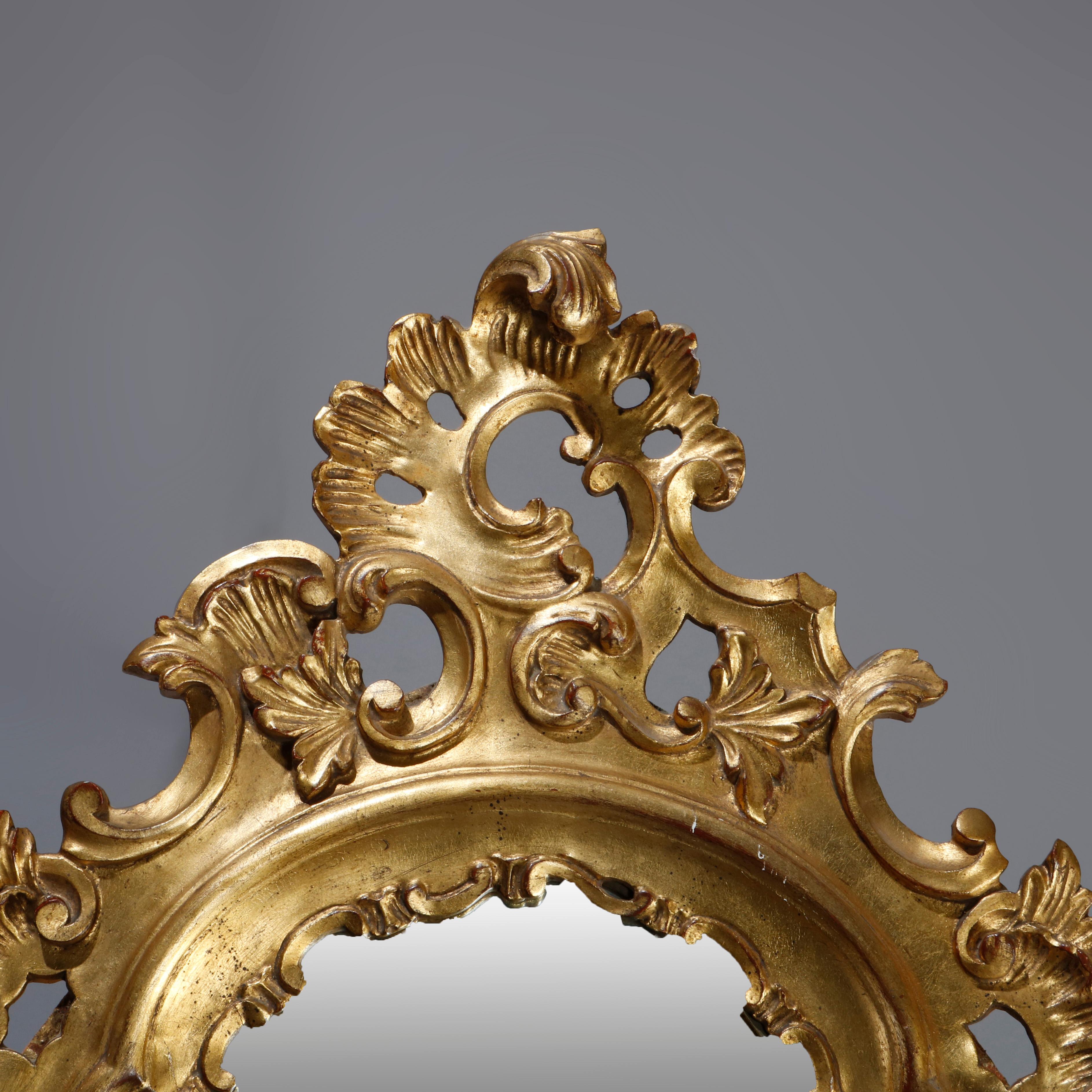 An oversized French Rococo wall mirror offers pierced giltwood frame with crest having central gadroon cartouche with flanking scroll and foliate elements surmounting shaped mirror, 20th century

***DELIVERY NOTICE – Due to COVID-19 we are employing