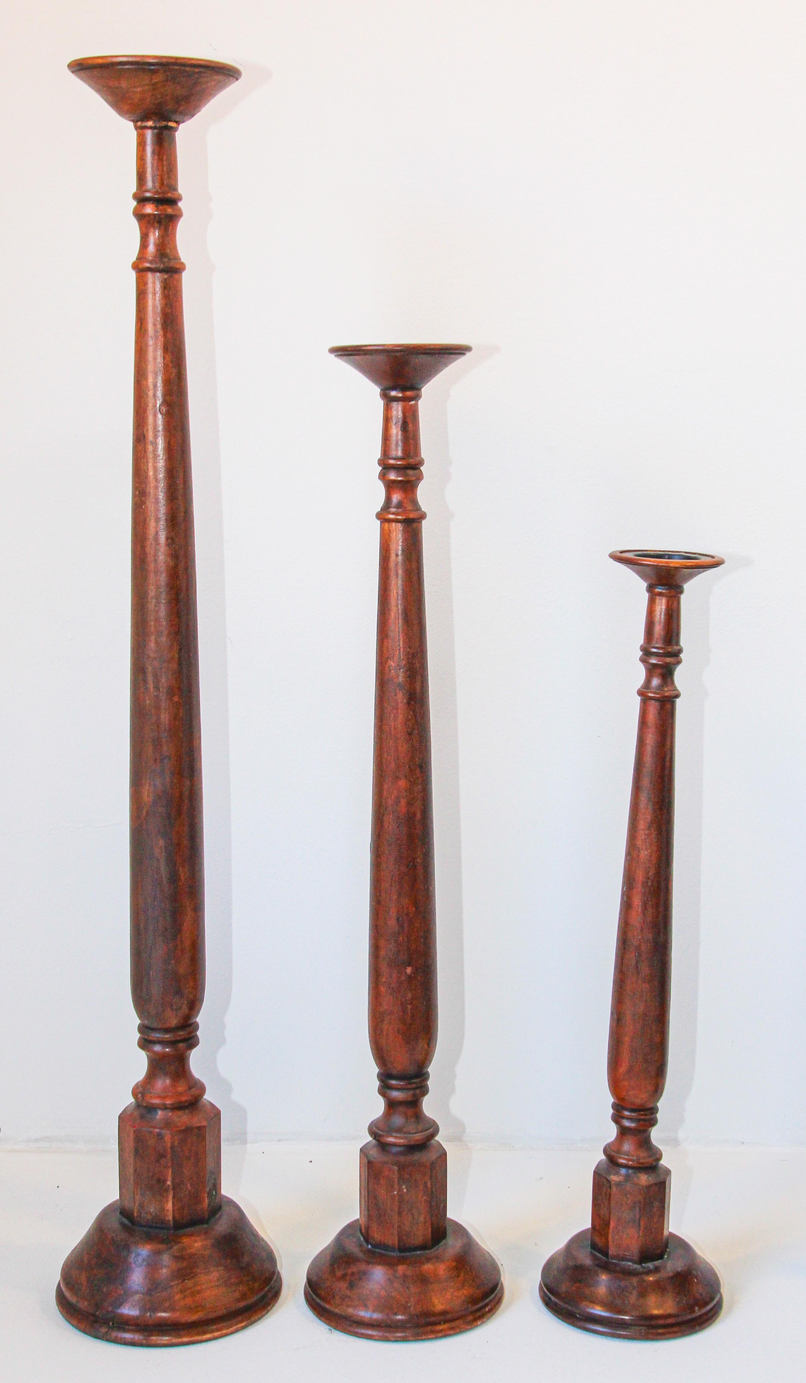 Jeu de trois porte-bougies piliers en bois de teck de tailles différentes.
Elégants chandeliers sculpturaux en bois tourné de style espagnol rustique sur des bases rondes. 
Elégant bougeoir en bois de teck tourné rustique avec une couleur et une