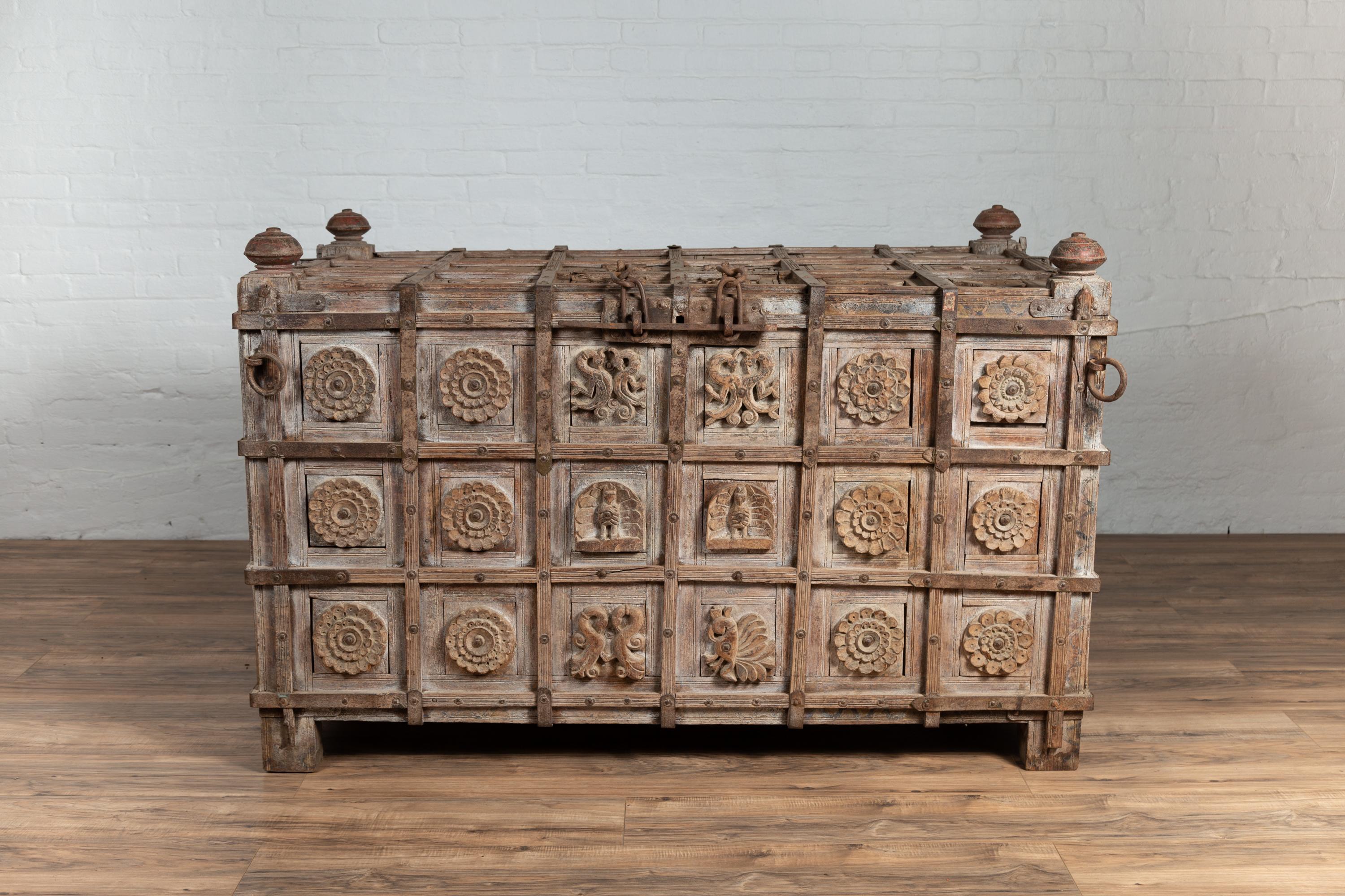An oversized and unusual Indian treasure chest from the 19th century, with raised X pattern design, carved rosettes and intertwining animals. It is hard not to be stricken by the amazing presence of this wooden treasure chest boasting great