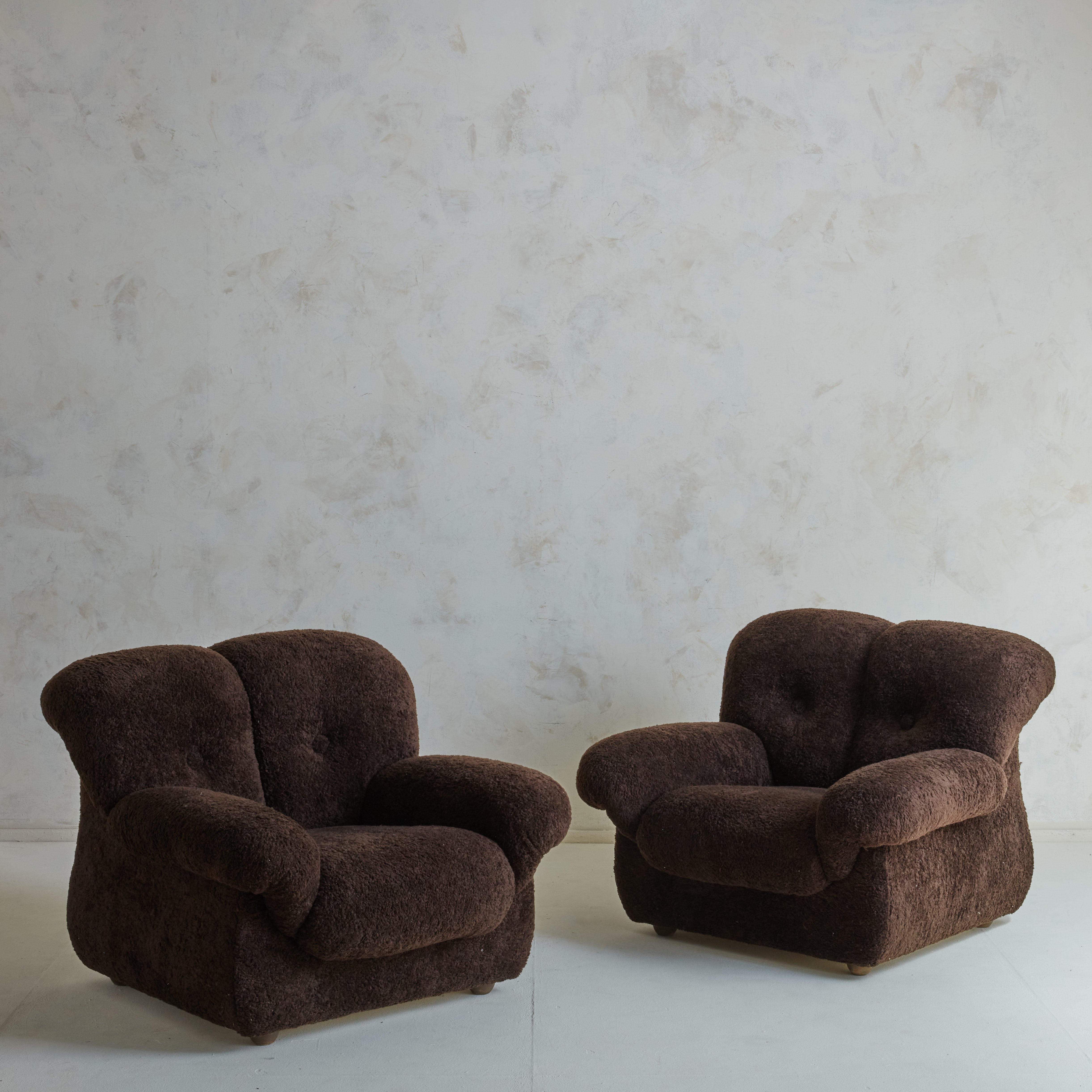 Large, oversized Italian lounge chair in brown teddy fabric with button tufts. The classic arm design of a traditional English sofa is adapted in these English rolled armchairs. The chair's wingback, which nearly seems to embrace the user, is