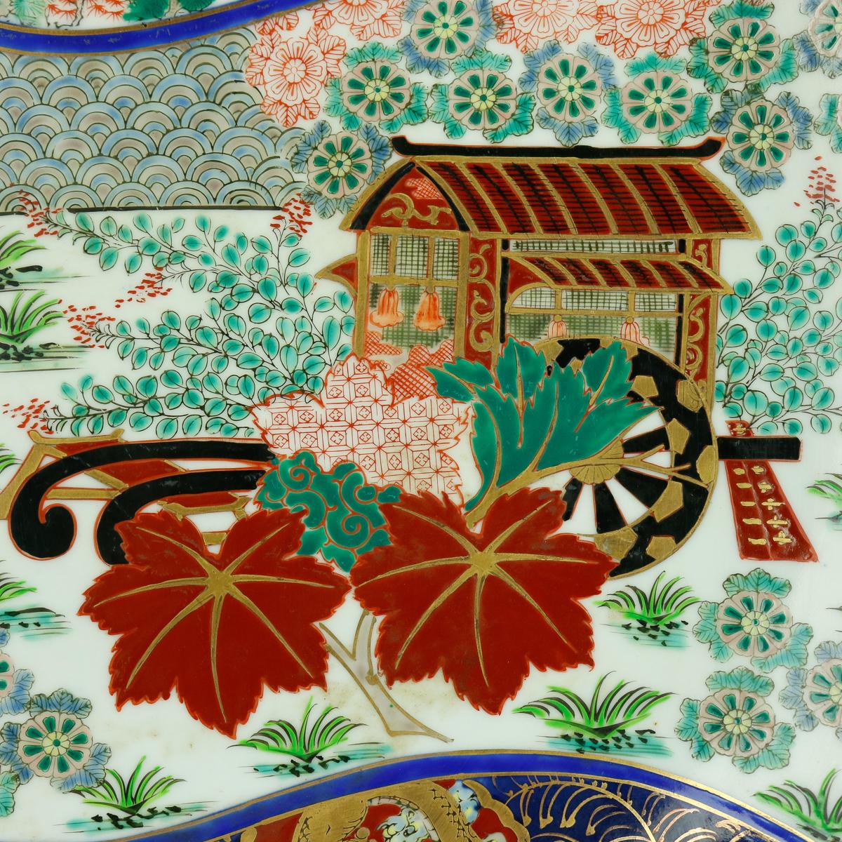 An oversized Japanese Imari porcelain charger offers hand painted reserve with pagoda, fan, garden landscape, dragon, scroll and foliate elements, gilt all-over highlights, en verso with rim scroll decoration and central signature, 20th