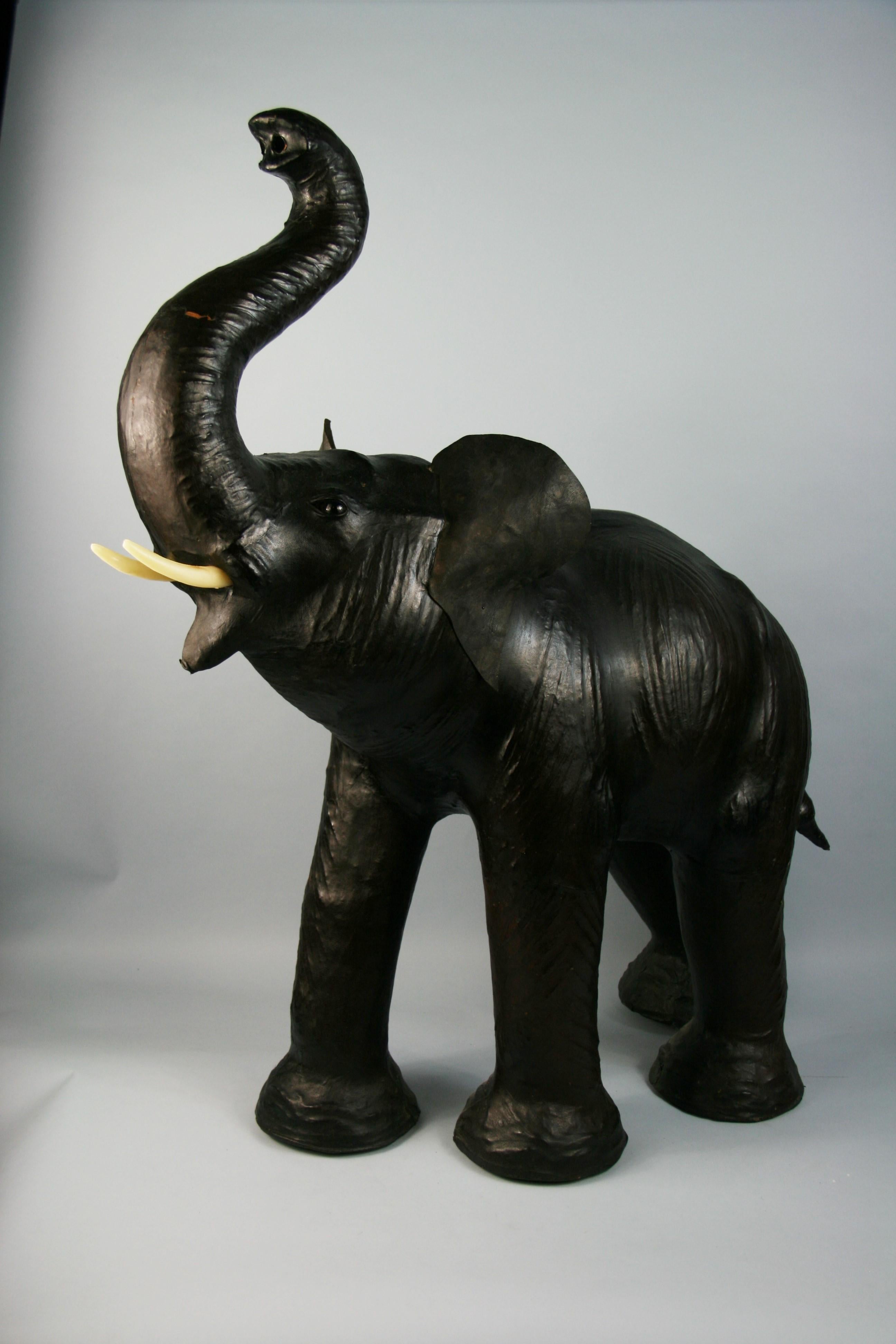3-529 oversized leather elephant foot stool on a carved wood base.
Attributed to Dimitri Omersa for Abercrombie and Fitch
Dimensions are from top of trunk to bottom of foot.
  