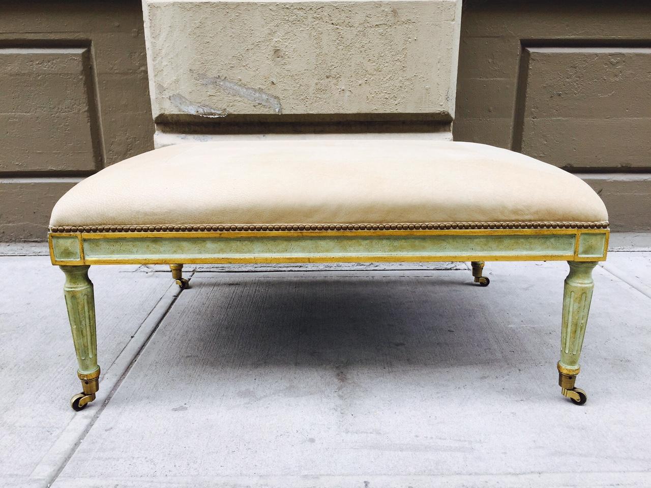 Oversized Louis XIV style ottoman with brass casters and upholstered in leather.