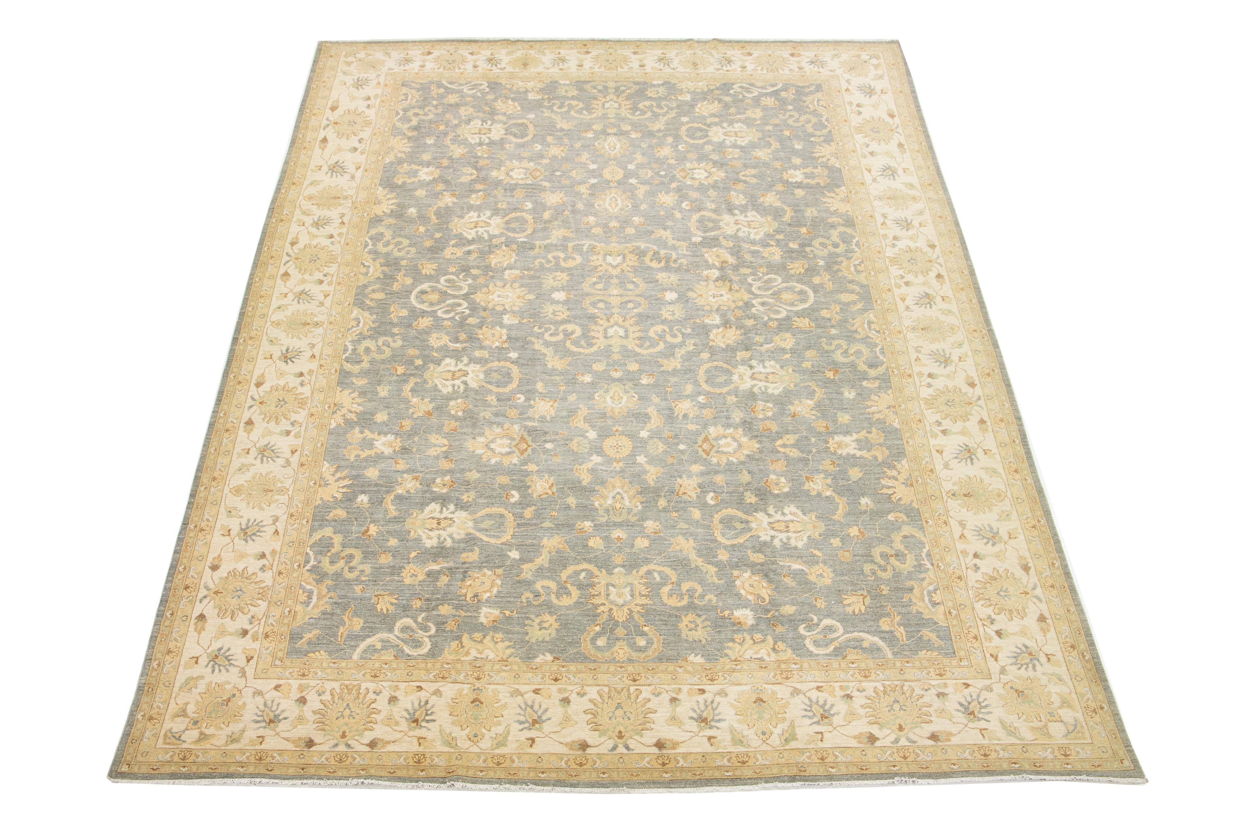 Dieser zeitgenössische Wollteppich im Oushak-Stil ist ein Beispiel für traditionelle Handwerkskunst. Der hellgraue Hintergrund ist kunstvoll mit einem floralen Muster verziert, in das sich elegante Beige-, Hellbraun- und Grüntöne nahtlos einfügen,