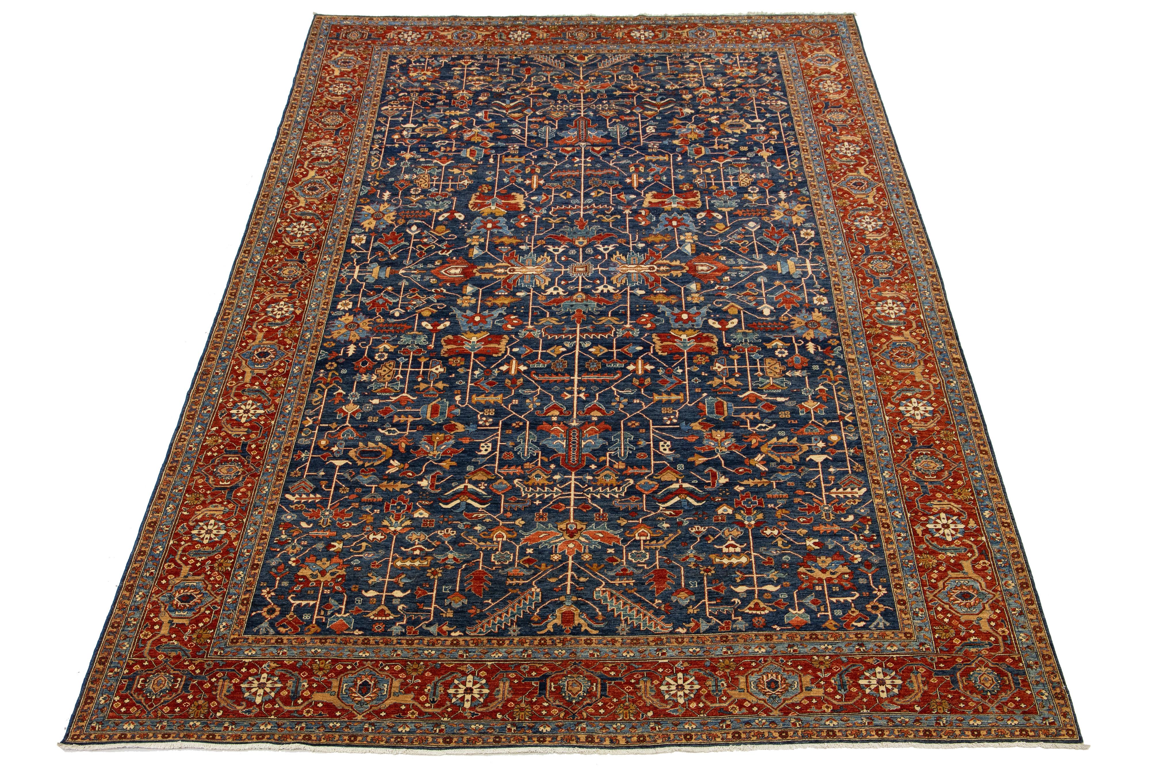 Dieser atemberaubende, übergroße Teppich zeigt eine moderne Interpretation des klassischen Serapi-Stils und ist aus hochwertiger Wolle gefertigt. Der elegante marineblaue Hintergrund ist mit einem lebhaften floralen Allover-Muster verziert, was ihn