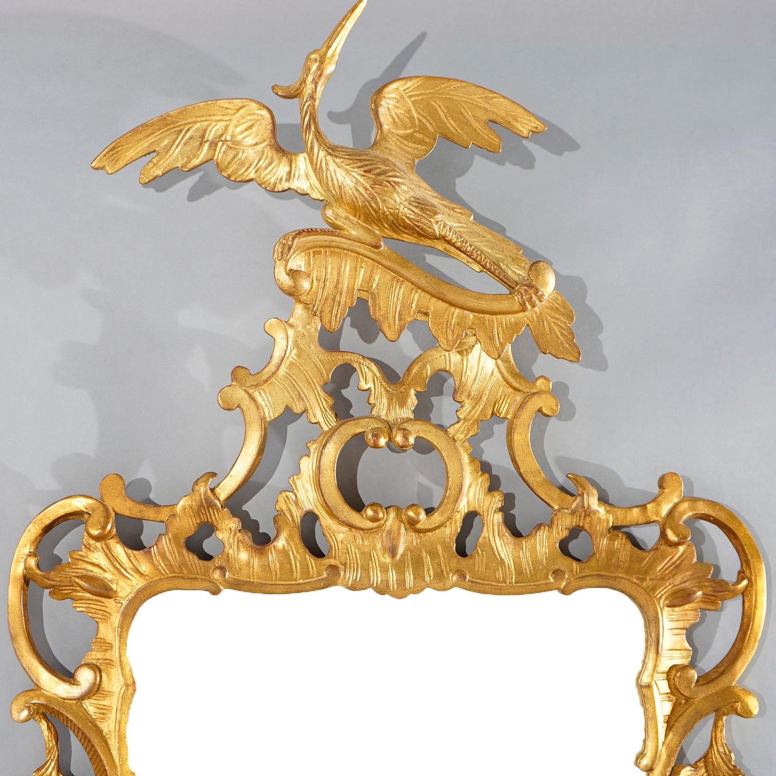A matching pair of large Chinese Chippendale style figural wall mirrors by Carver's Guild offers foliate form pierced giltwood frames with phoenix (or eagle) finials, en verso maker labels, 20th century

Measures- 59.25''H x 26''W x 4''D; 57.5''H x