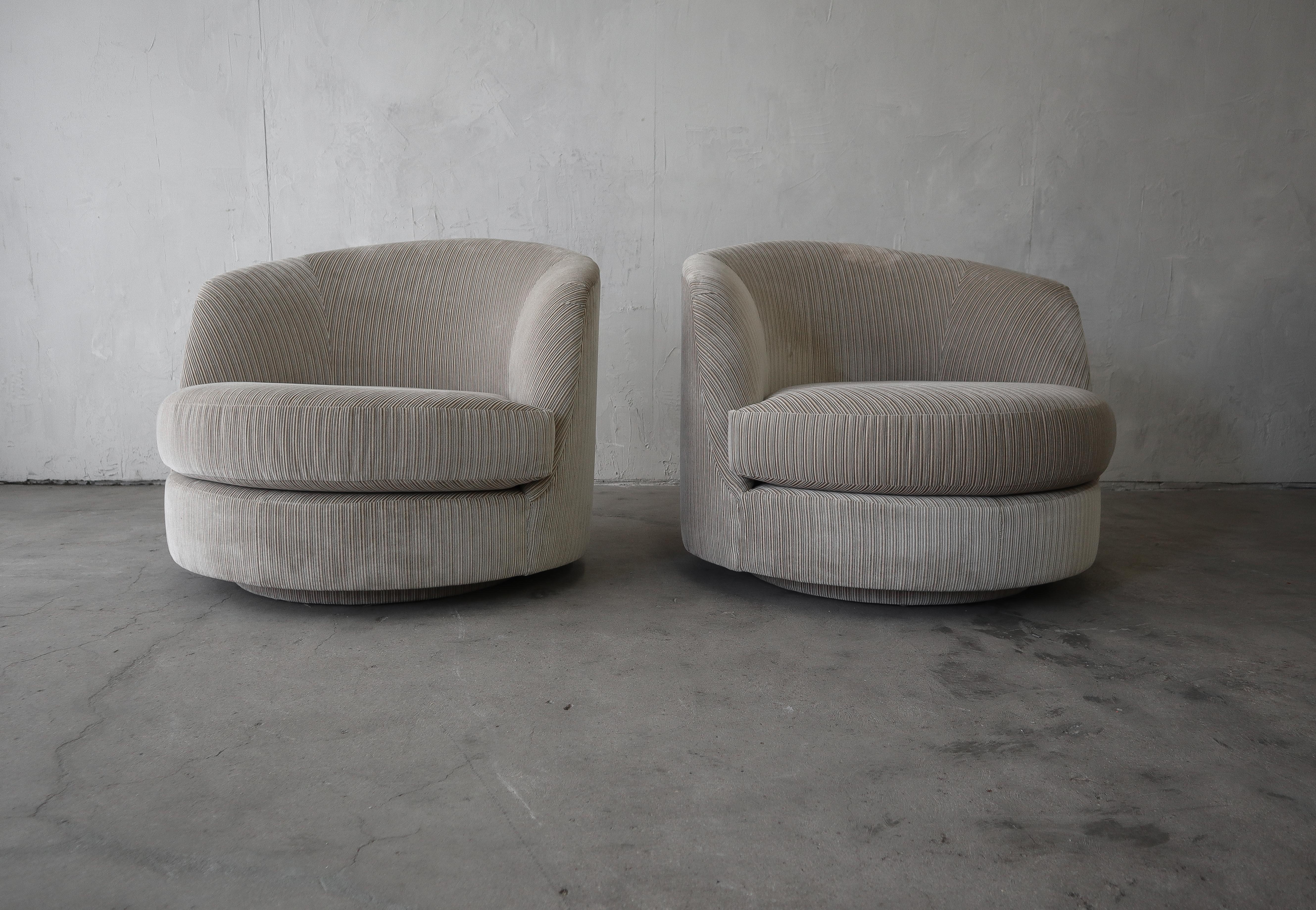 Nice pair of oversized midcentury swivel barrel chairs. Chairs swivel on a raised upholstered plinth.

Chairs sold as found and reupholstery is recommended due to a large light spot on the back of one chair, see last image. All mechanism are solid