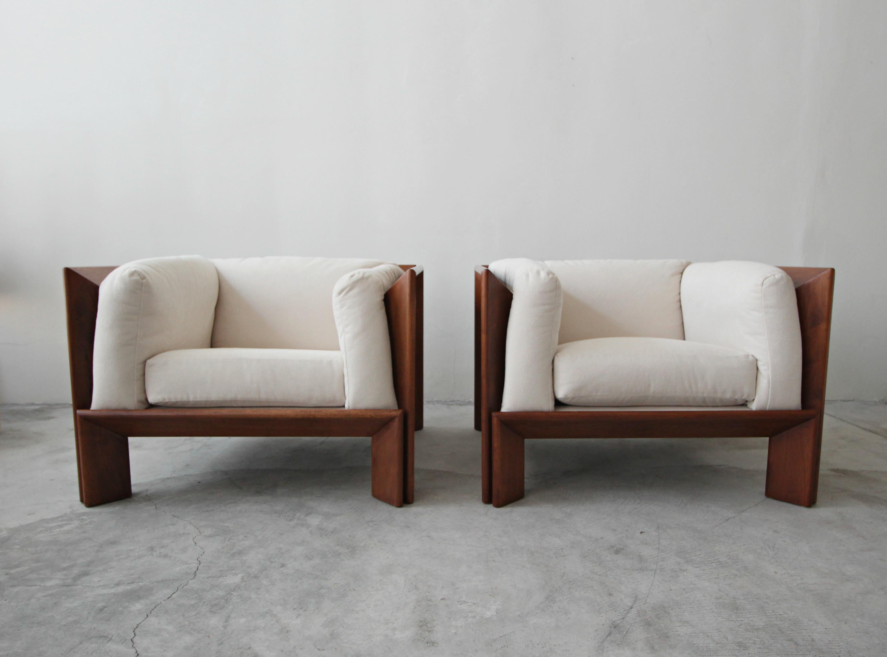 Super rare pair of oversized, angular, solid walnut lounge chairs. These chairs are like no others, simple but so complex. The lines created by their solid walnut frames make these two furniture masterpieces. These chairs feature a cozy seating area