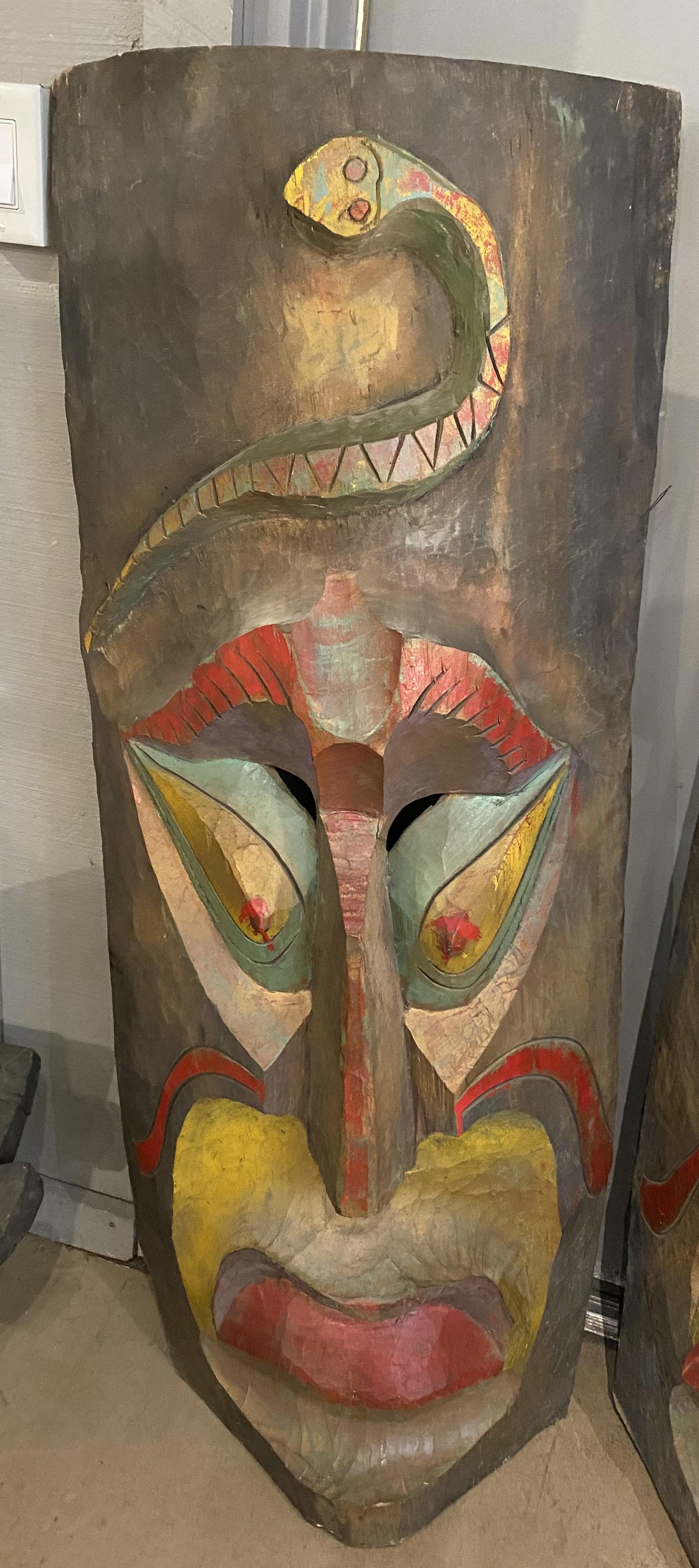 Magnifique paire de suspensions murales de style Tiki en bois polychrome surdimensionné sculpté à la main avec des serpents au-dessus des visages, datant du milieu à la fin du 20e siècle. Probablement du Mexique. Très bon état général, avec des
