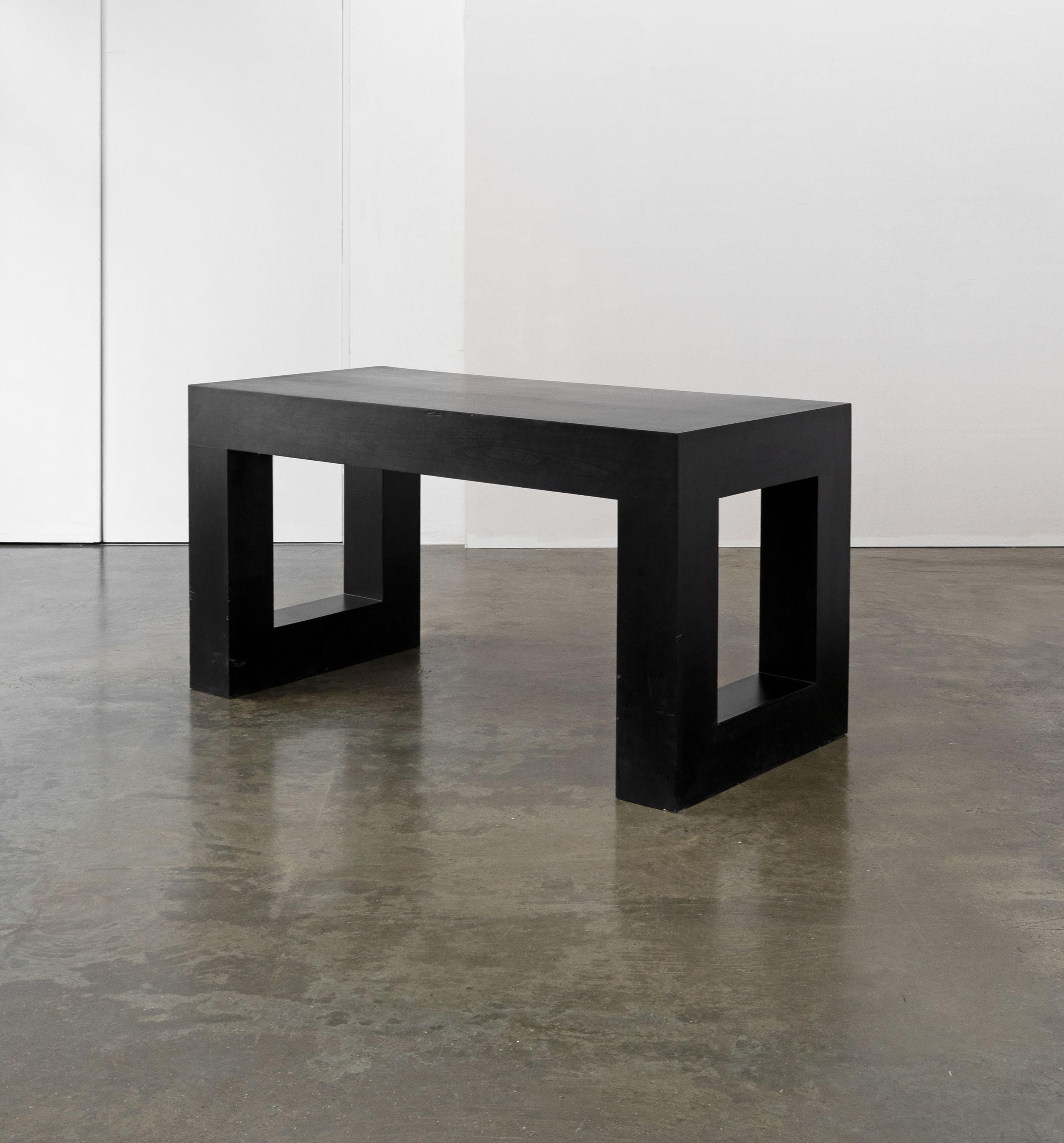 A late 20th Century desk made from black lacquered wood and featuring an oversized cuboid frame and brass handles. 

Dimensions (cm, approx):
Height: 77
Width: 150
Depth: 70

Condition: In fair condition with scuffs and minor surface losses. Please