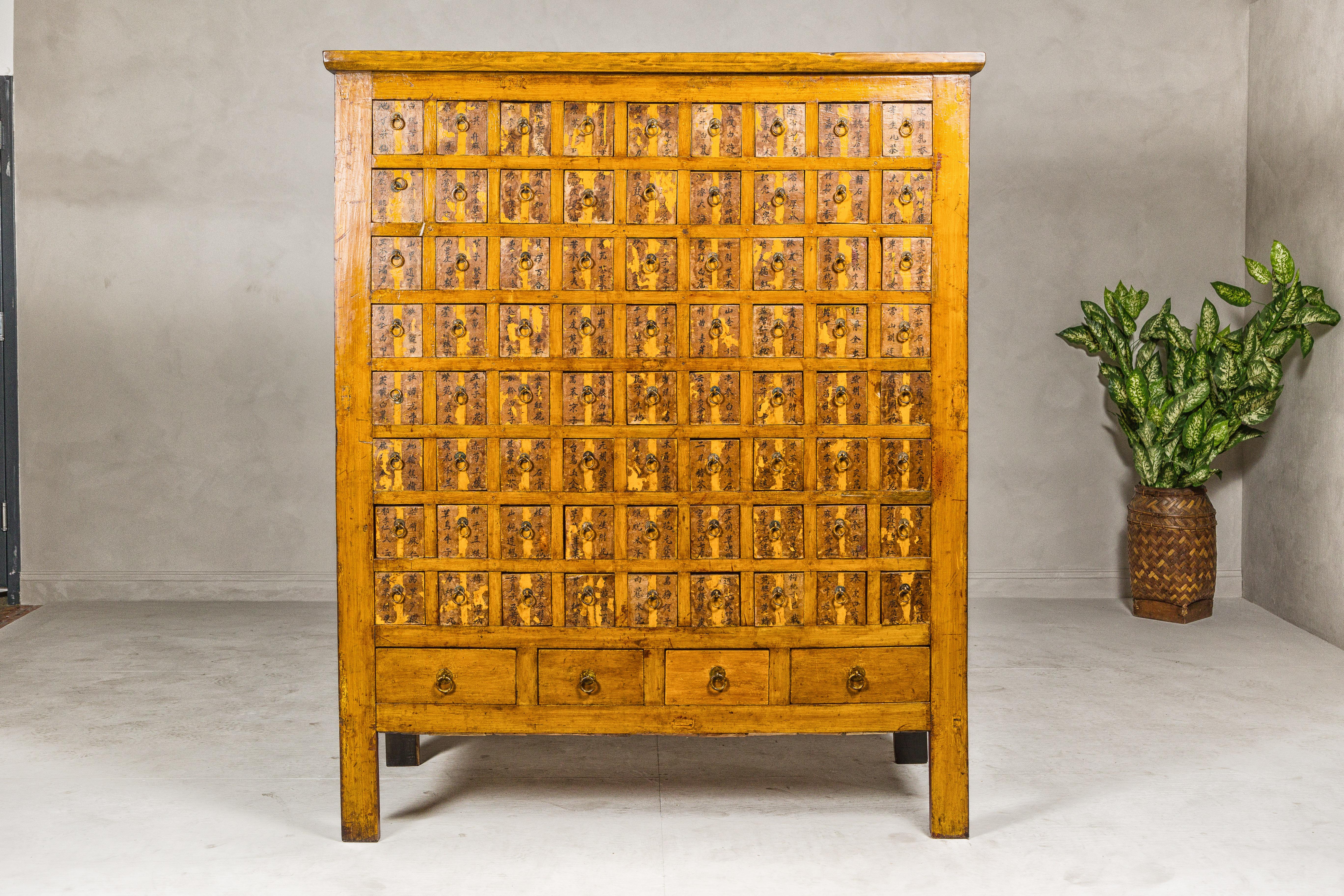An oversized Qing Dynasty period apothecary cabinet from the 19th century with 72 small drawers, four medium sized ones, hand-painted calligraphy and weathered lacquered finish. This monumental Qing Dynasty apothecary cabinet, hailing from the 19th