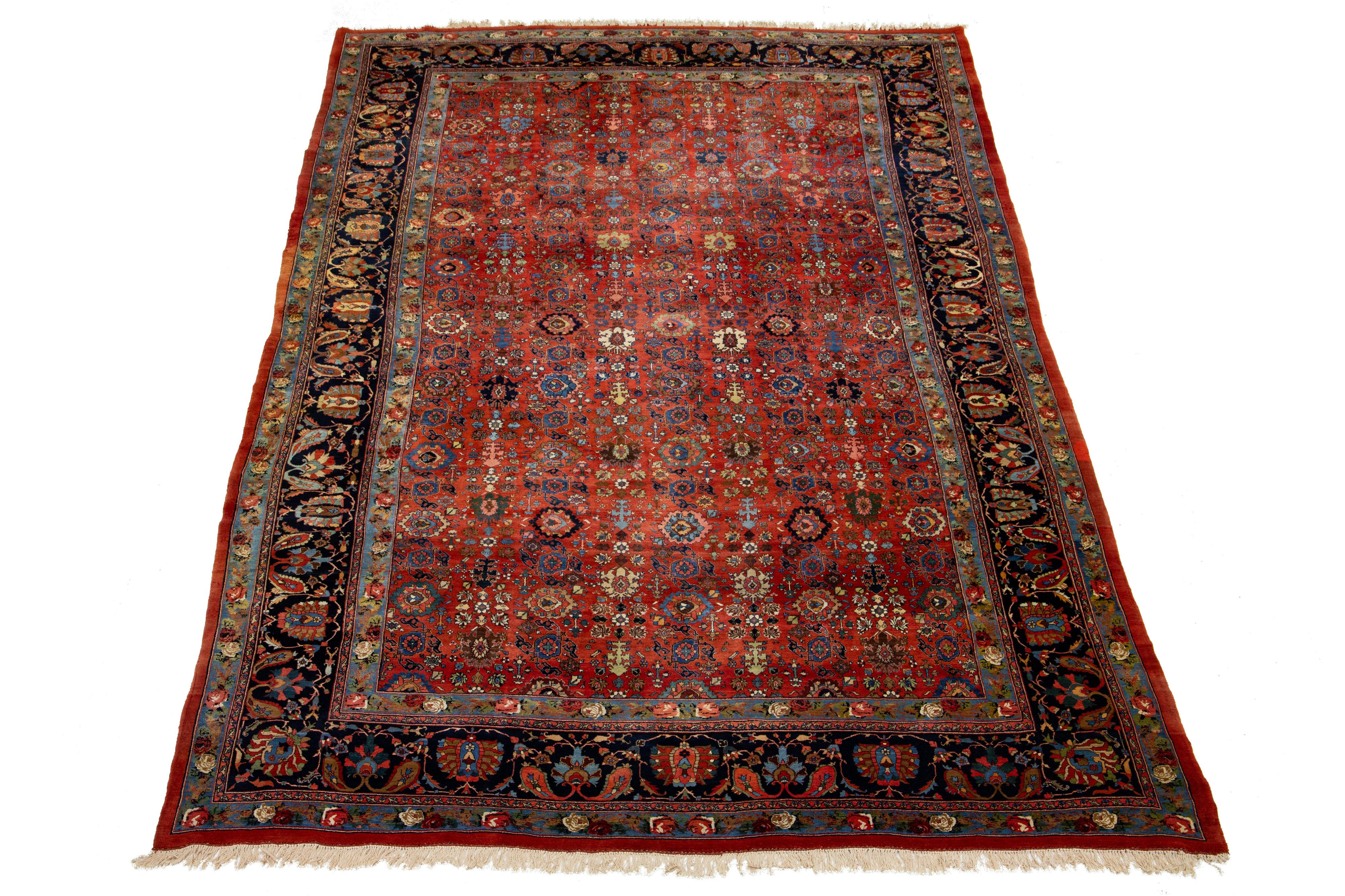 Ce tapis ancien surdimensionné en laine persane Bidjar possède un charme remarquable. Il présente de la laine nouée à la main dans un champ rouge vif, complété par un motif floral enrichi d'accents multicolores.

Ce tapis mesure 12'9