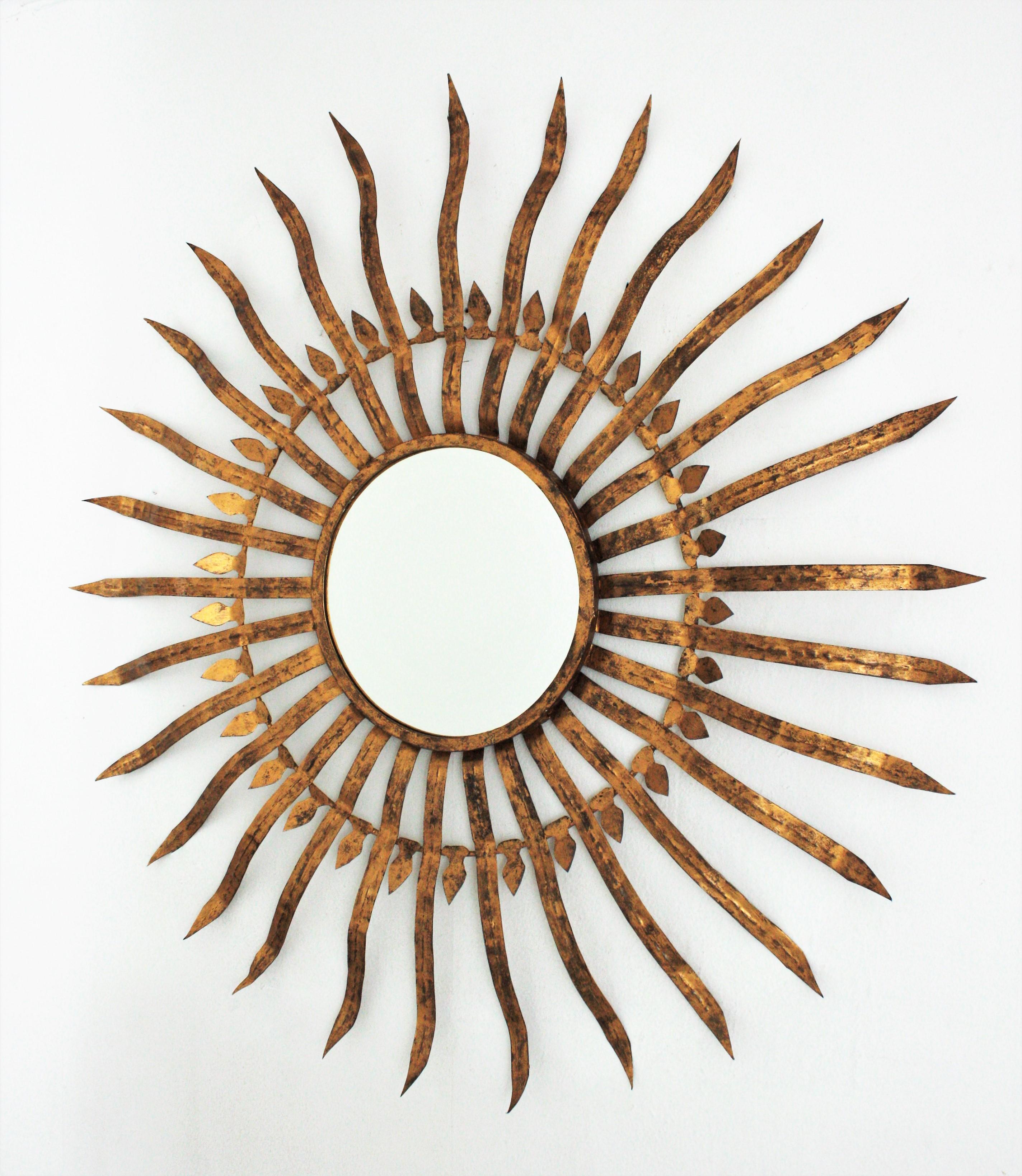 Outstanding Hollywood Regency gilt wrought iron convex sunburst mirror, Spain 1950s
Extra large size (40.15 inches) and convex glass mirror. It has a terrific aged patina with gold leaf gilding.
This magnificent hand-hammered sunburst wall mirror