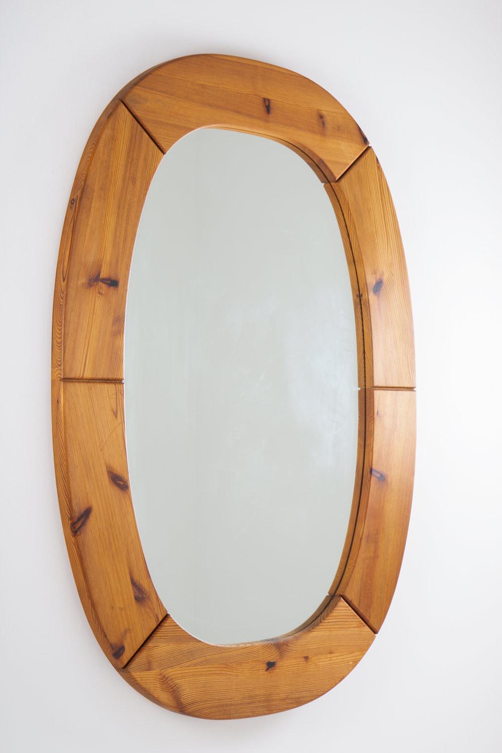 Mirror by Swedish manufacturer Glasmäster Markaryd.
With the simple lines, large proportions and naturally patinated wood, this is a great example of Swedish Brutalist pine furniture from the 1970s. The mirror is oval-shaped with a thick wooden