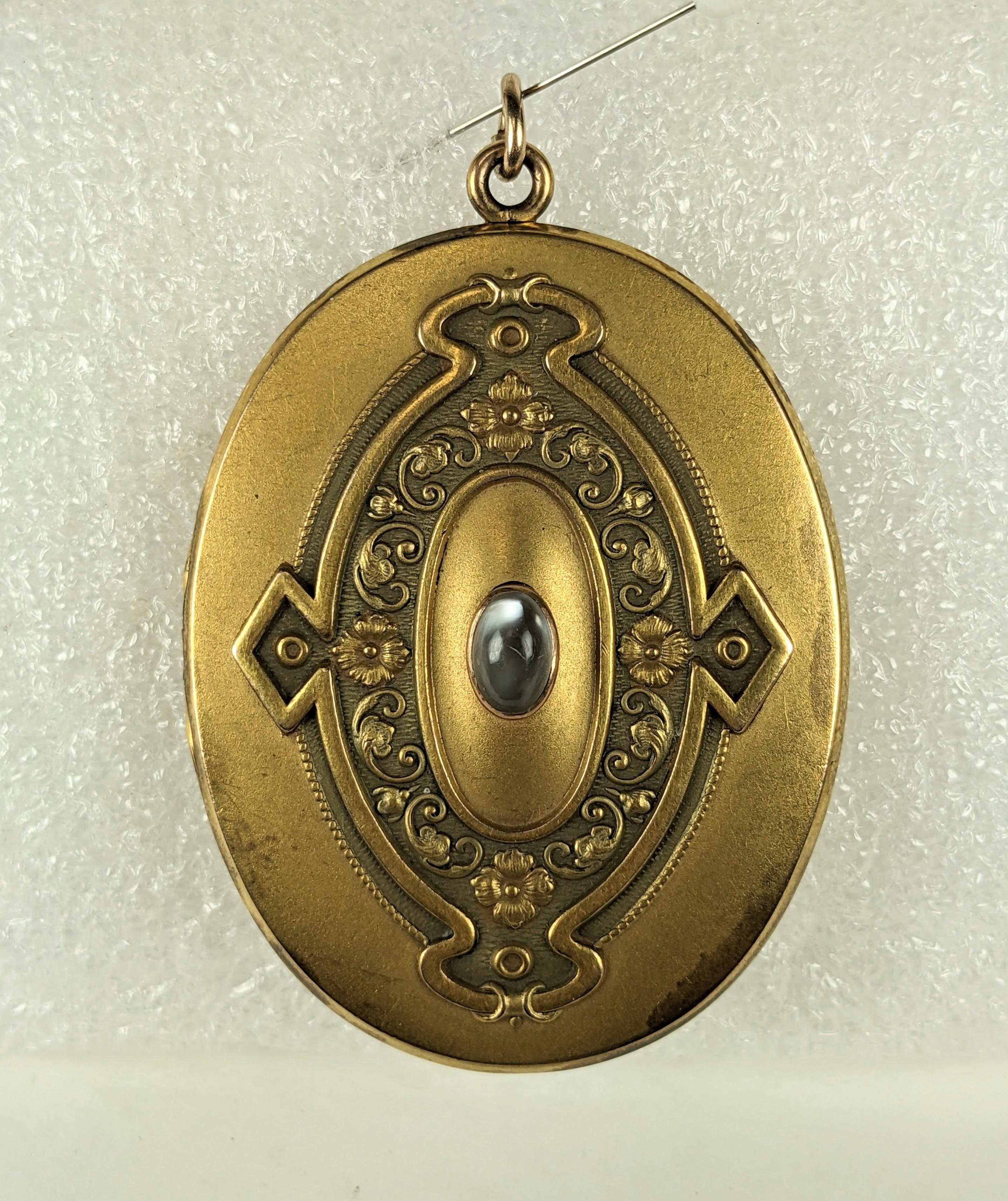 Oversized Victorian Gold Filled Locket with Moonstone from the late 19th Century. Art Nouveau floral design with genuine moonstone. Large scale with original pics of a young man from a later period, 1920's. 
2.5