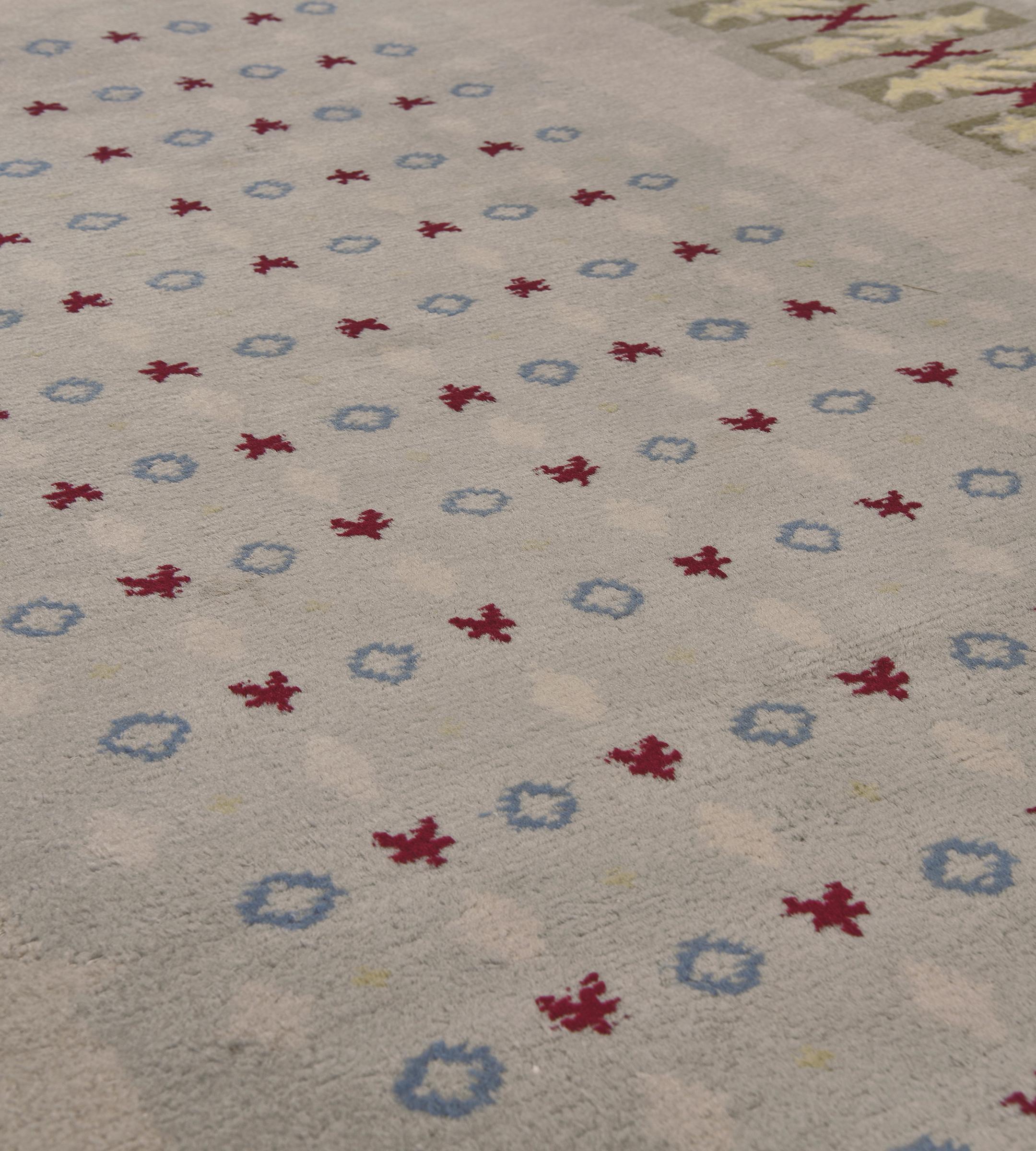 Dieser französische Leleu-Teppich im Vintage-Stil, ca. 1950, hat ein einfarbiges, blassgraues Feld mit einem zentralen, großen, blaugrauen Feld mit horizontalen Reihen kleiner blauer Kreise und burgunderroten Blumenmotiven, die sich mit Reihen