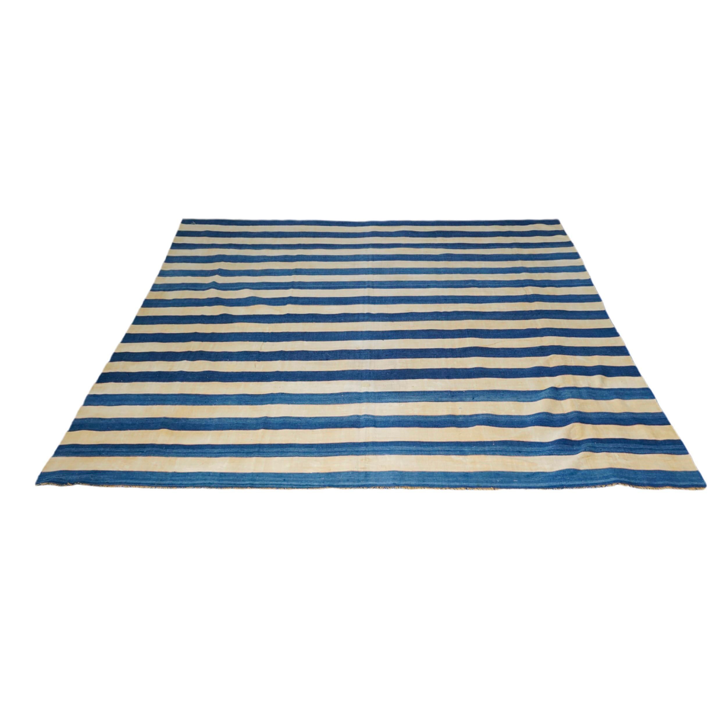 Esta alfombra Dhurrie vintage de 11x12 es una nueva y emocionante selección de la última adquisición de Rug & Kilim de raras y ejemplares telas planas de mediados de siglo del mismo estilo, tejidas en algodón en la India hacia 1950-1960. 

Sobre el