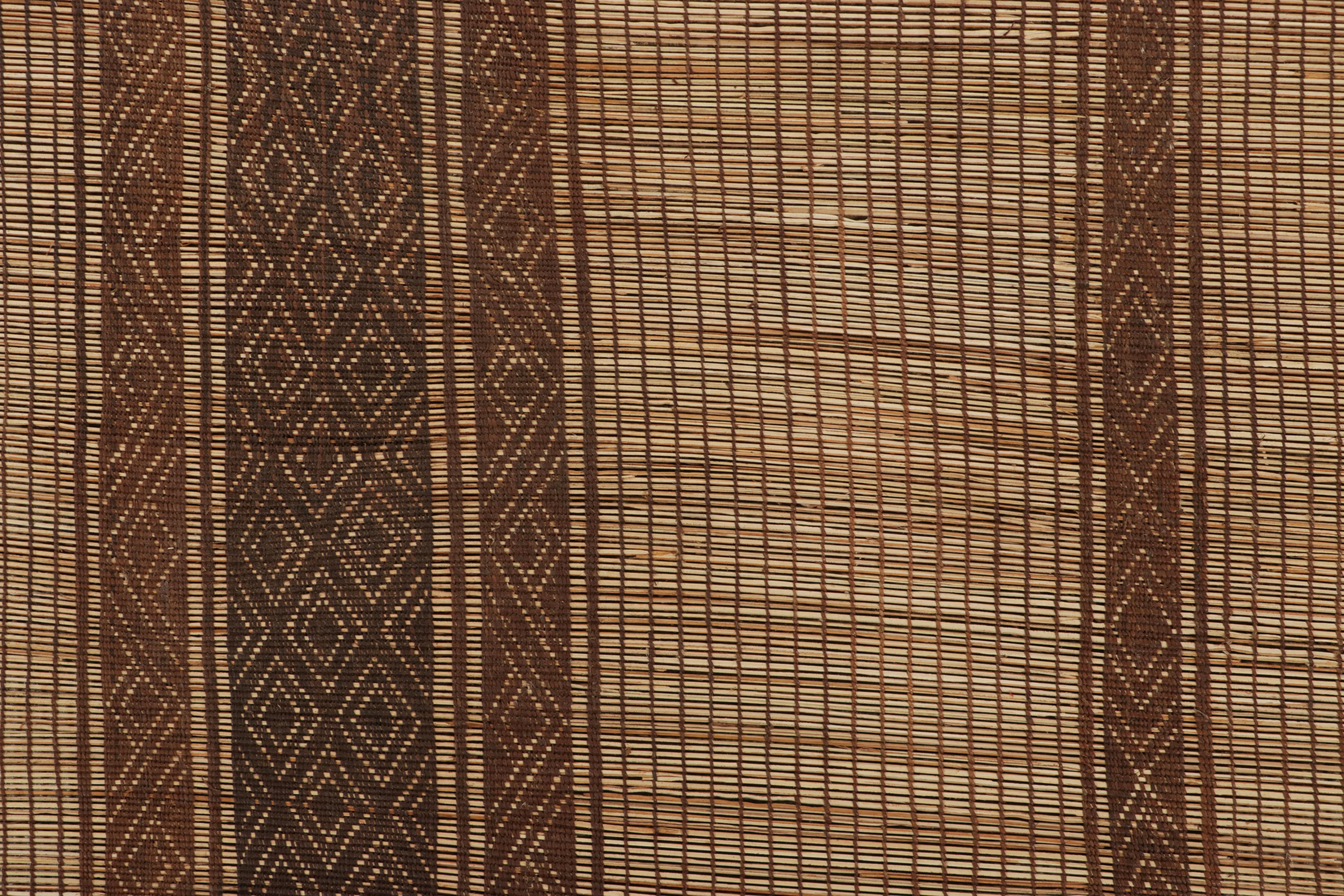 Questo rivestimento vintage è una rara stuoia Tuareg 14x17 di grandi dimensioni, realizzata dagli omonimi tessitori tribali nomadi. Intrecciata a mano con canne e pelle in Mauritania intorno al 1950-1960, i suoi materiali naturali si esprimono nei