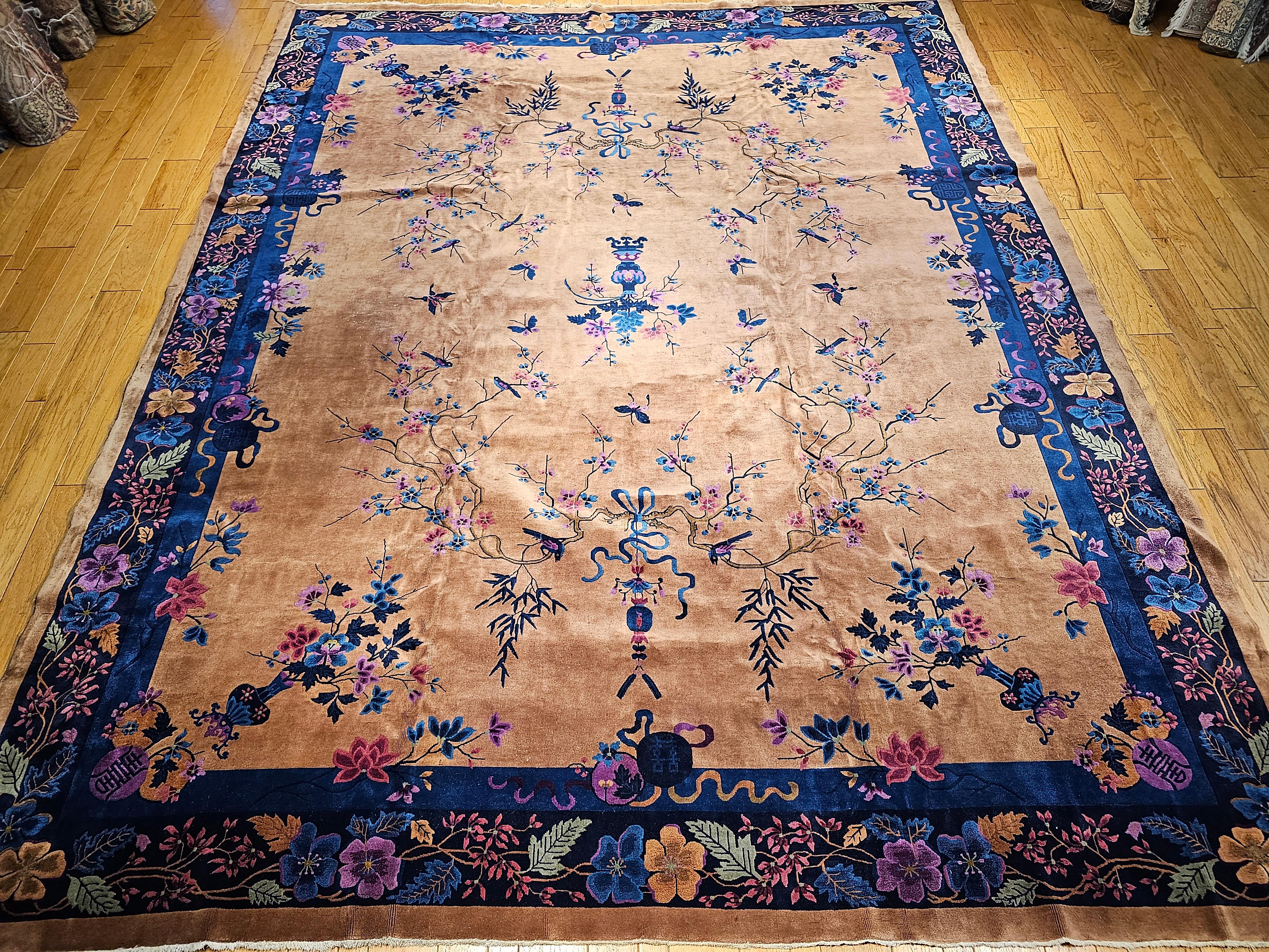The extremely rare palace size Walter Nichols Art Deco Chinese rug in a tan or camelhair color background with floral patterns in pink, blue, red, and lavender.  The rug is from the 1st quarter of the 20th century and is around 100 years old and is